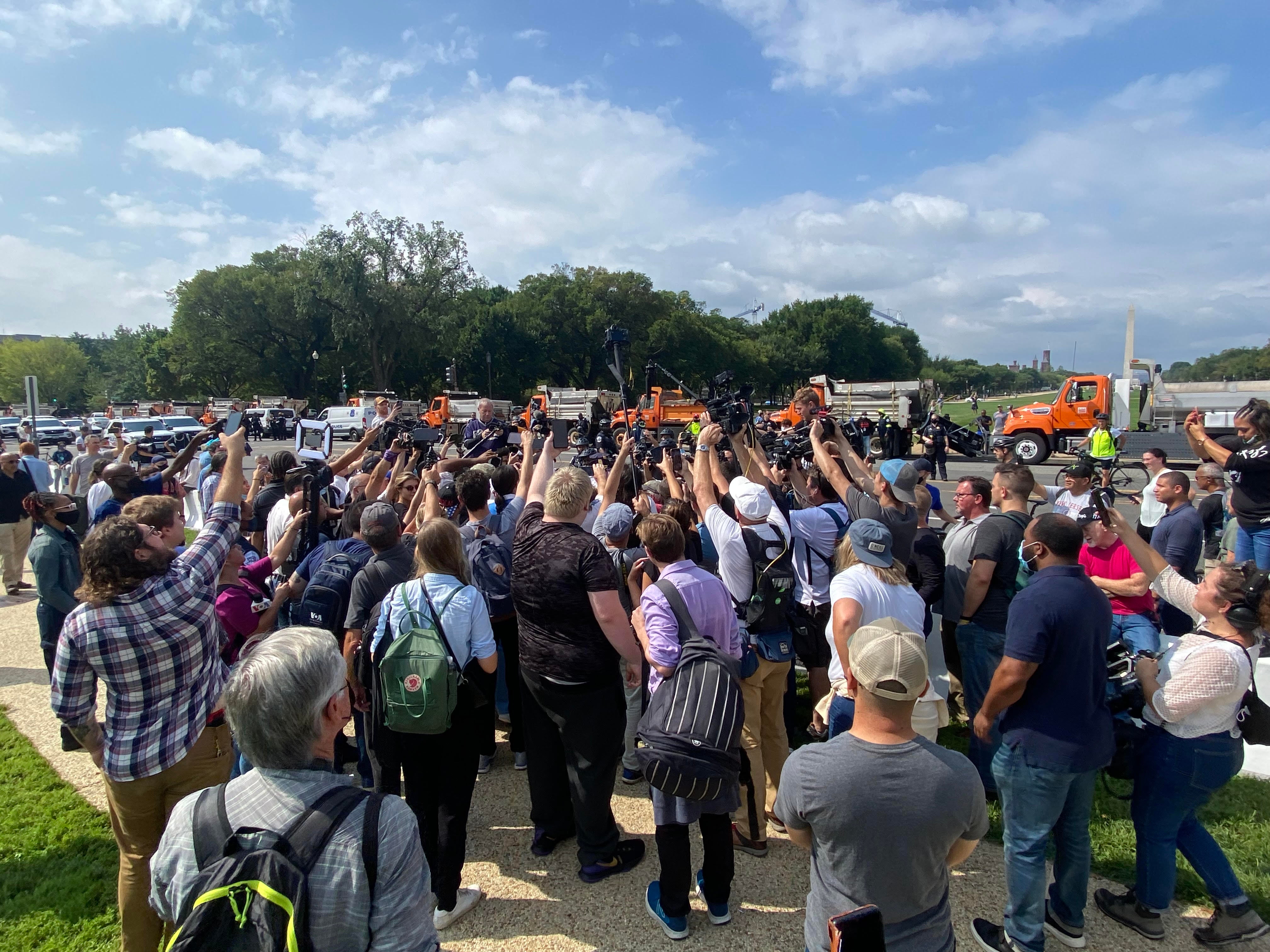 Journalists surround a protester and counter-protester at a rally in support of January 6 detainees on Saturday.