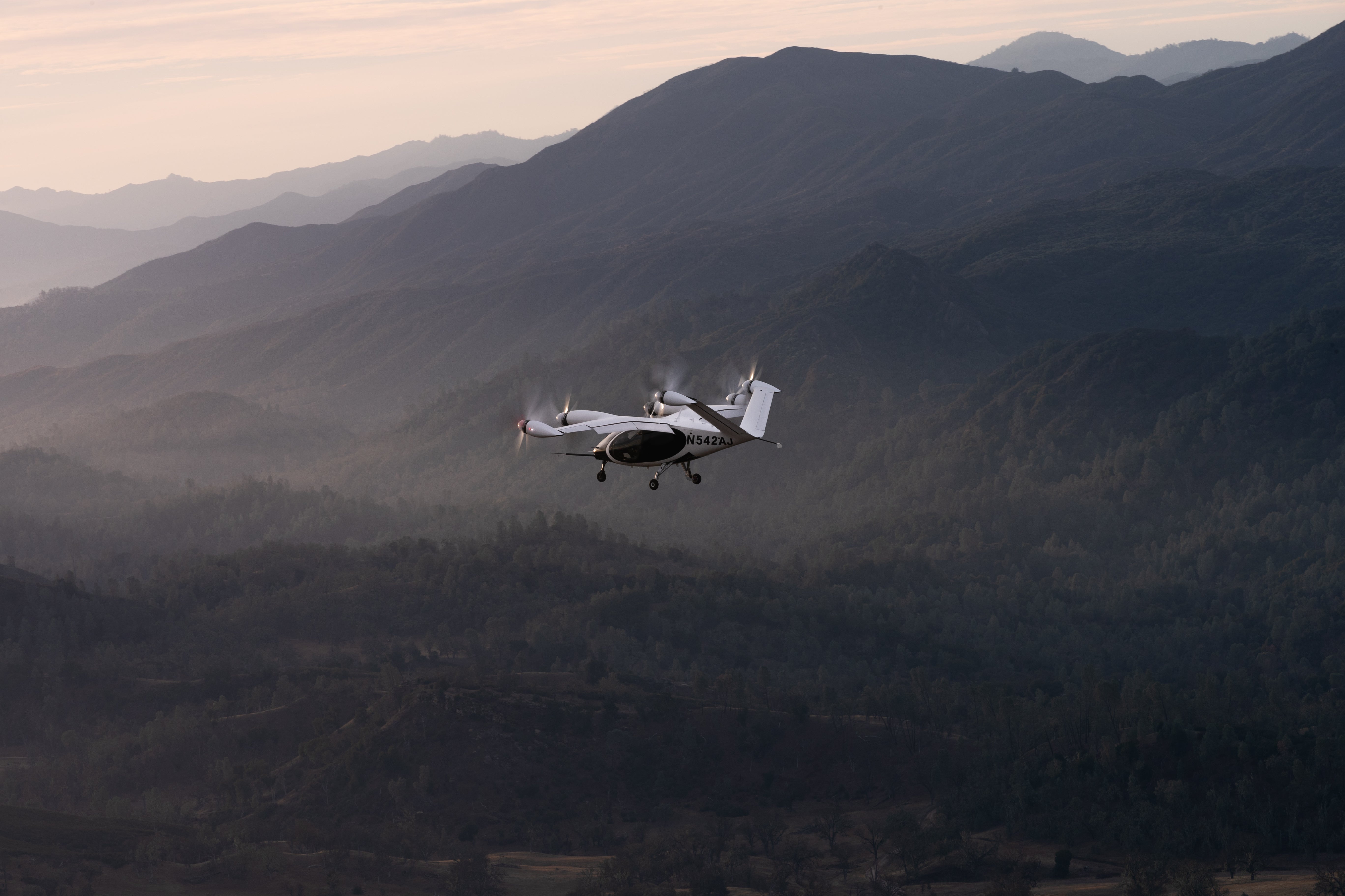 A Joby Aviation eVTOL aircraft flies above the countryside.