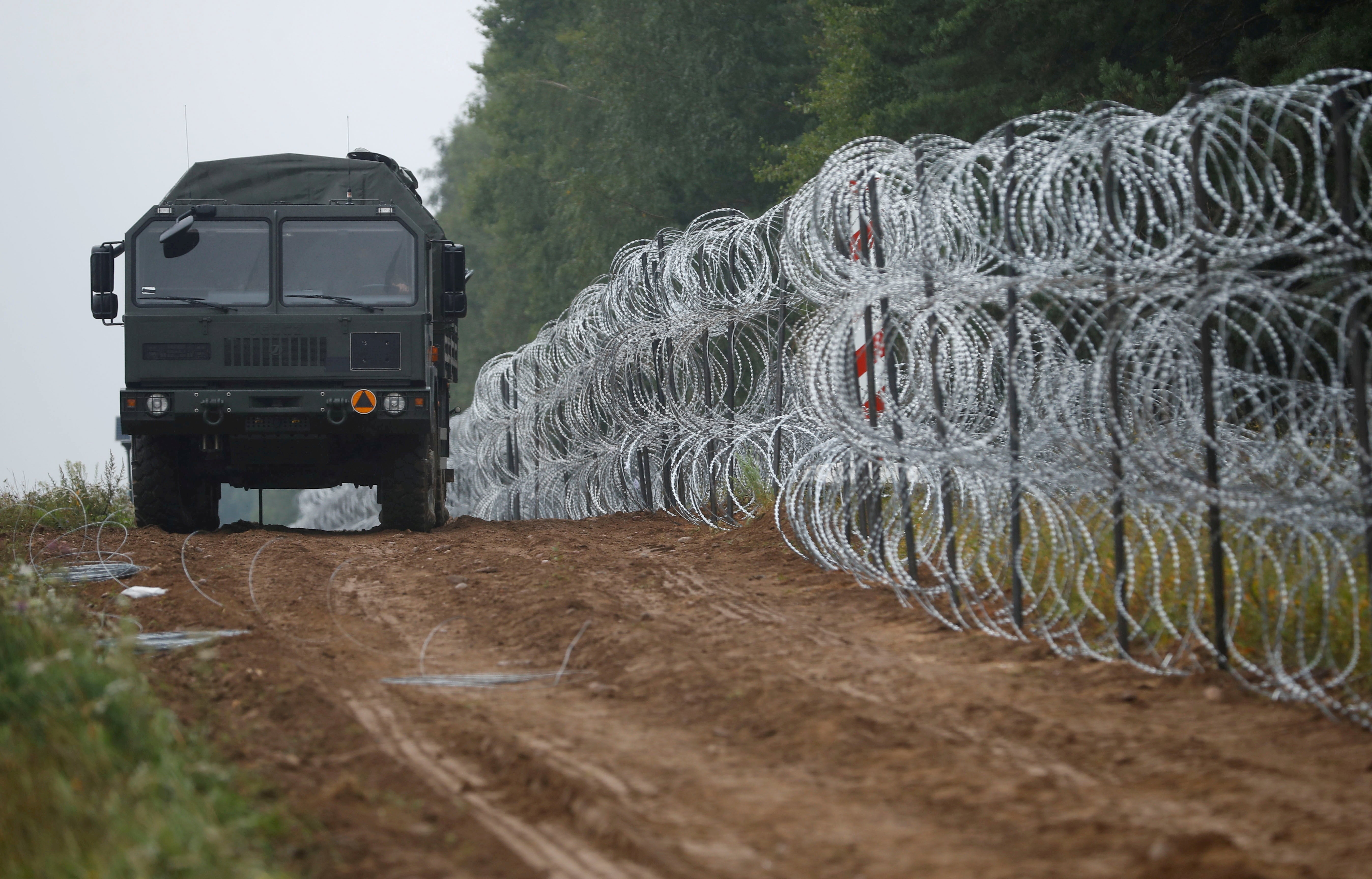 A view of a vehicle next to a fence built by Polish soldiers on the border between Poland and Belarus