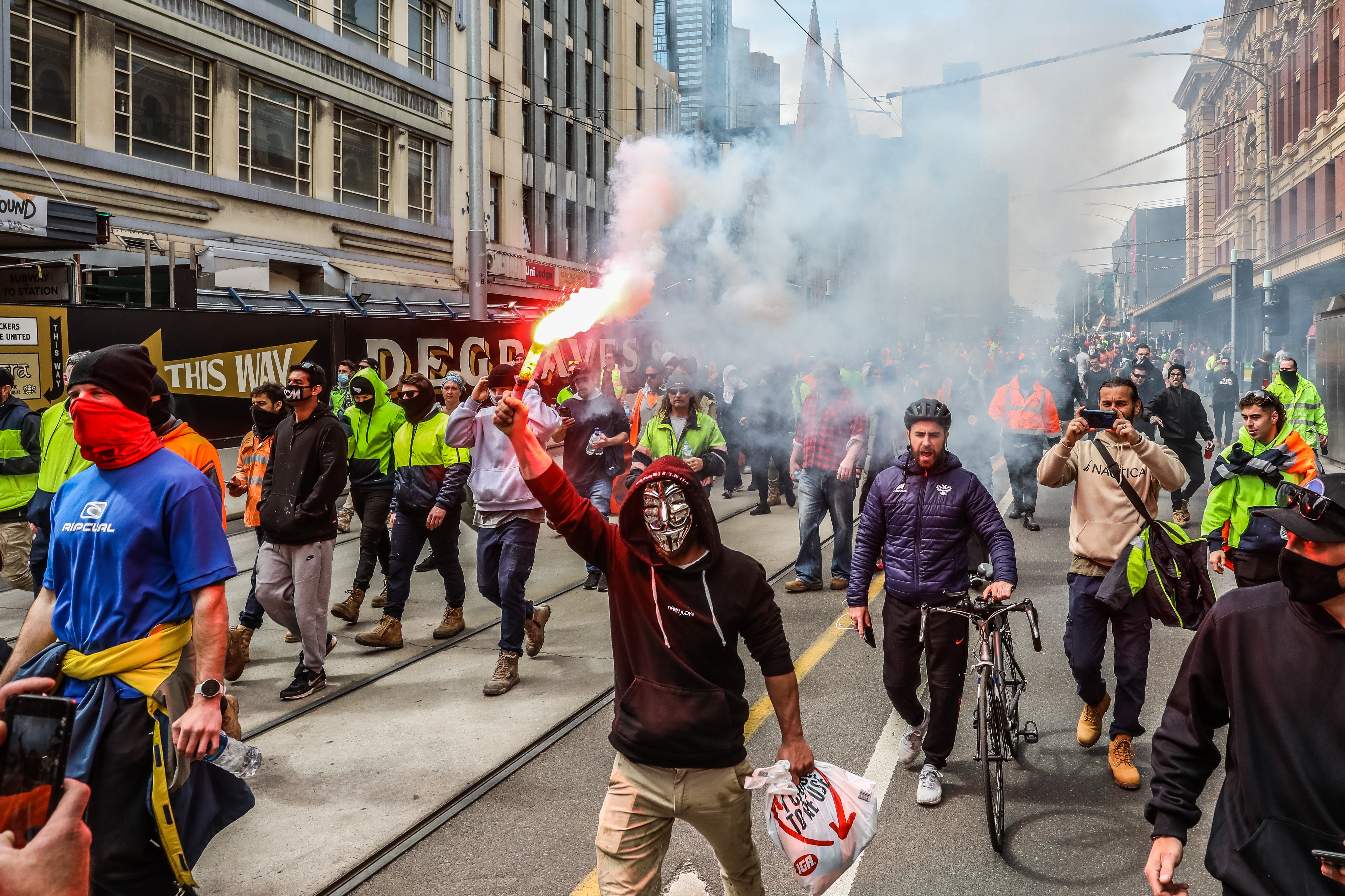 A protester lights a flare as thousands march through Melbourne after the state government announced construction shutdown on 21 September 2021