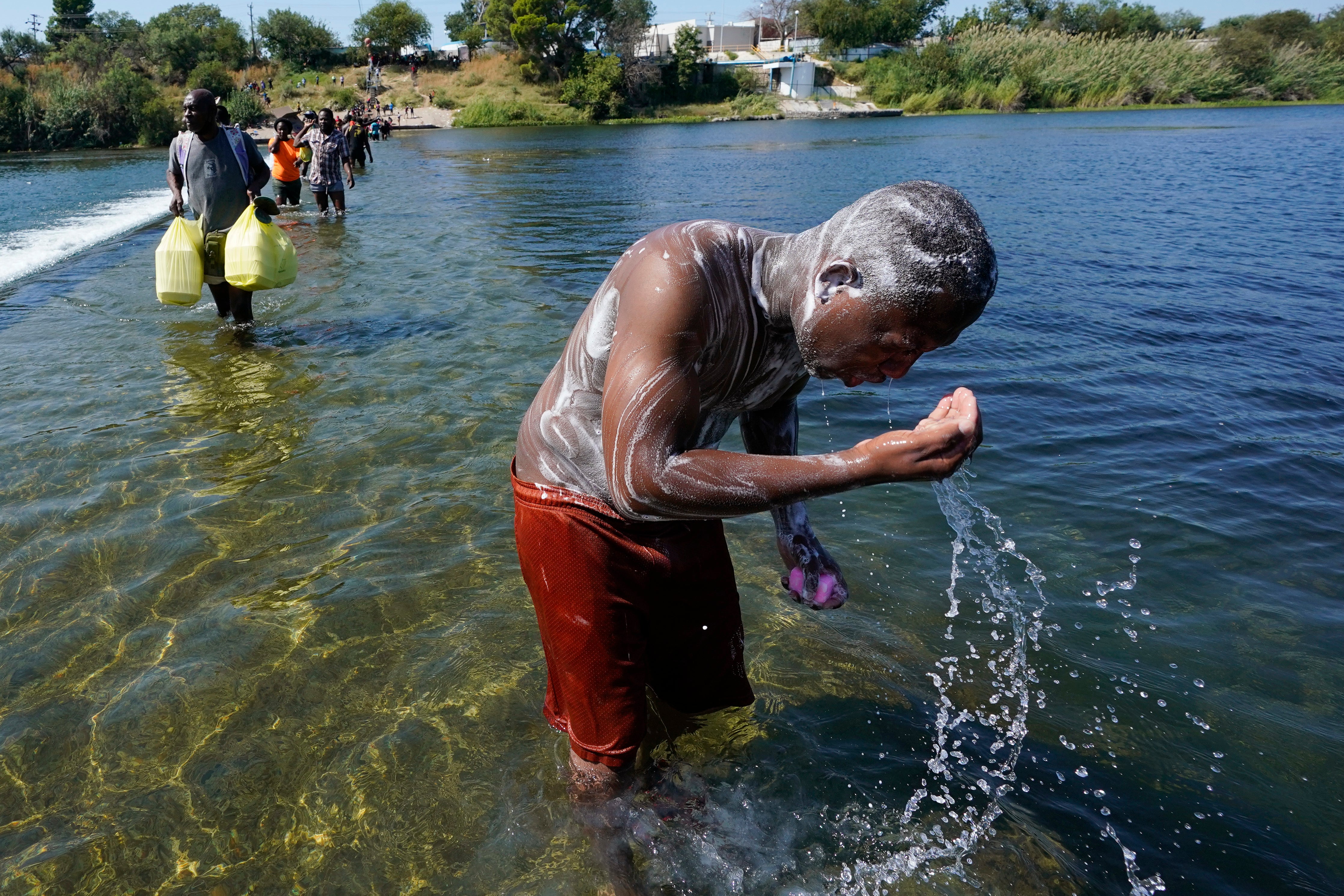 A Haitian migrant uses the Rio Grande to take a bath after crossing a dam from Mexico to the United States, Friday, 17 September 2021, in Del Rio, Texas