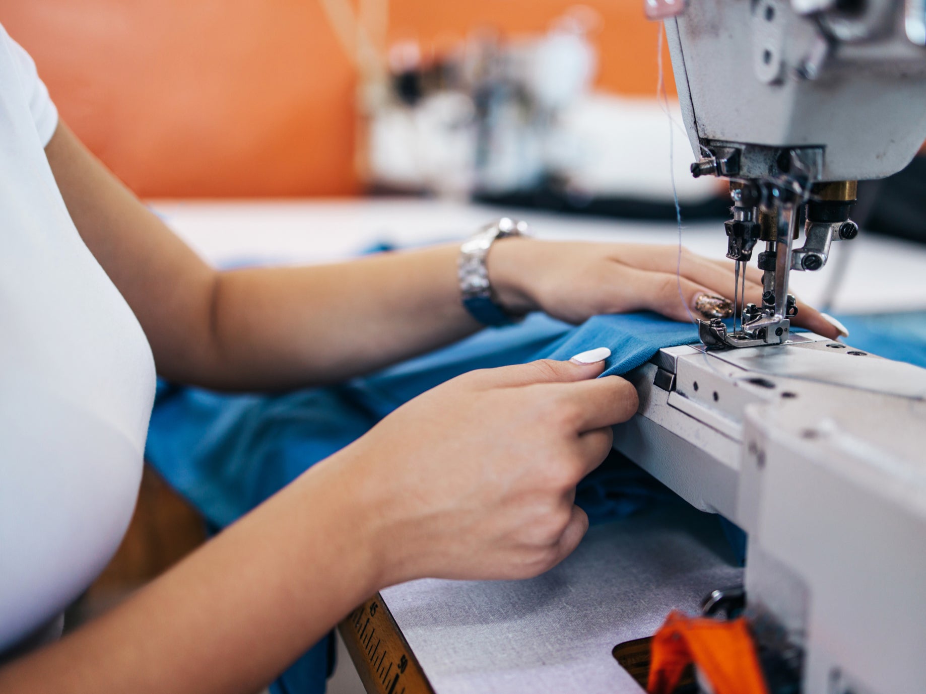 A person repairs a piece of clothing with a sewing machine