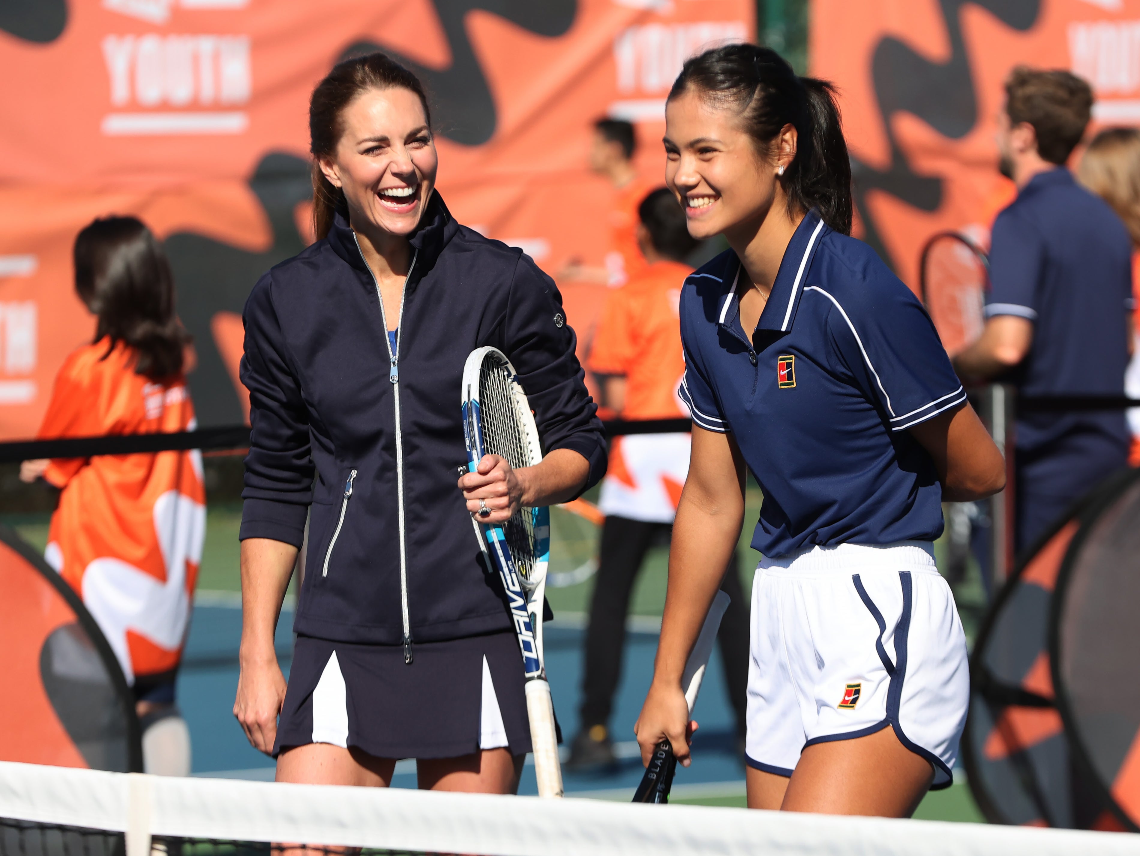 Kate Middleton laughs as she plays tennis with Emma Raducanu (R)