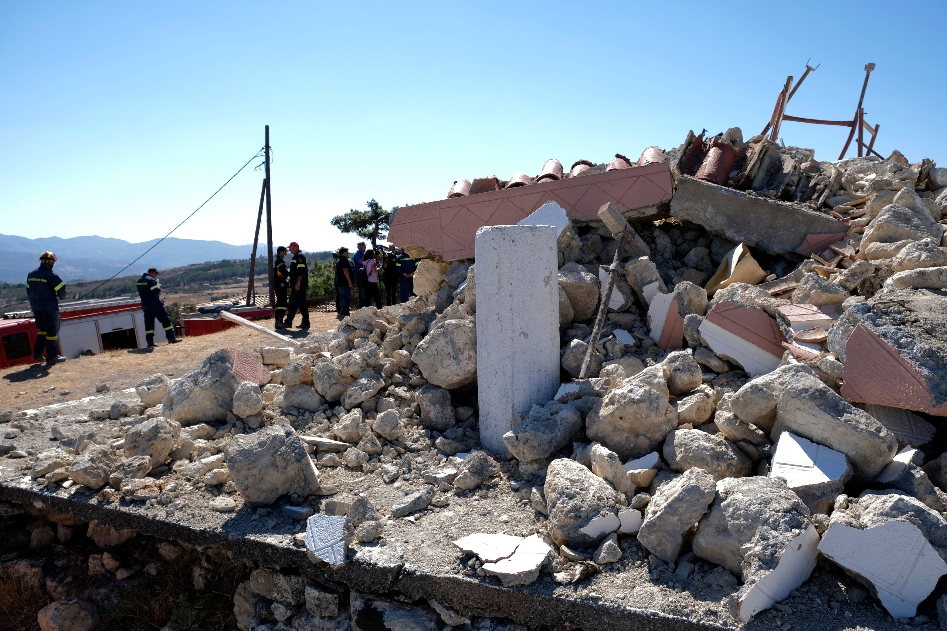 Firefighters stand next to a demolished Greek Orthodox church of Profitis Ilias