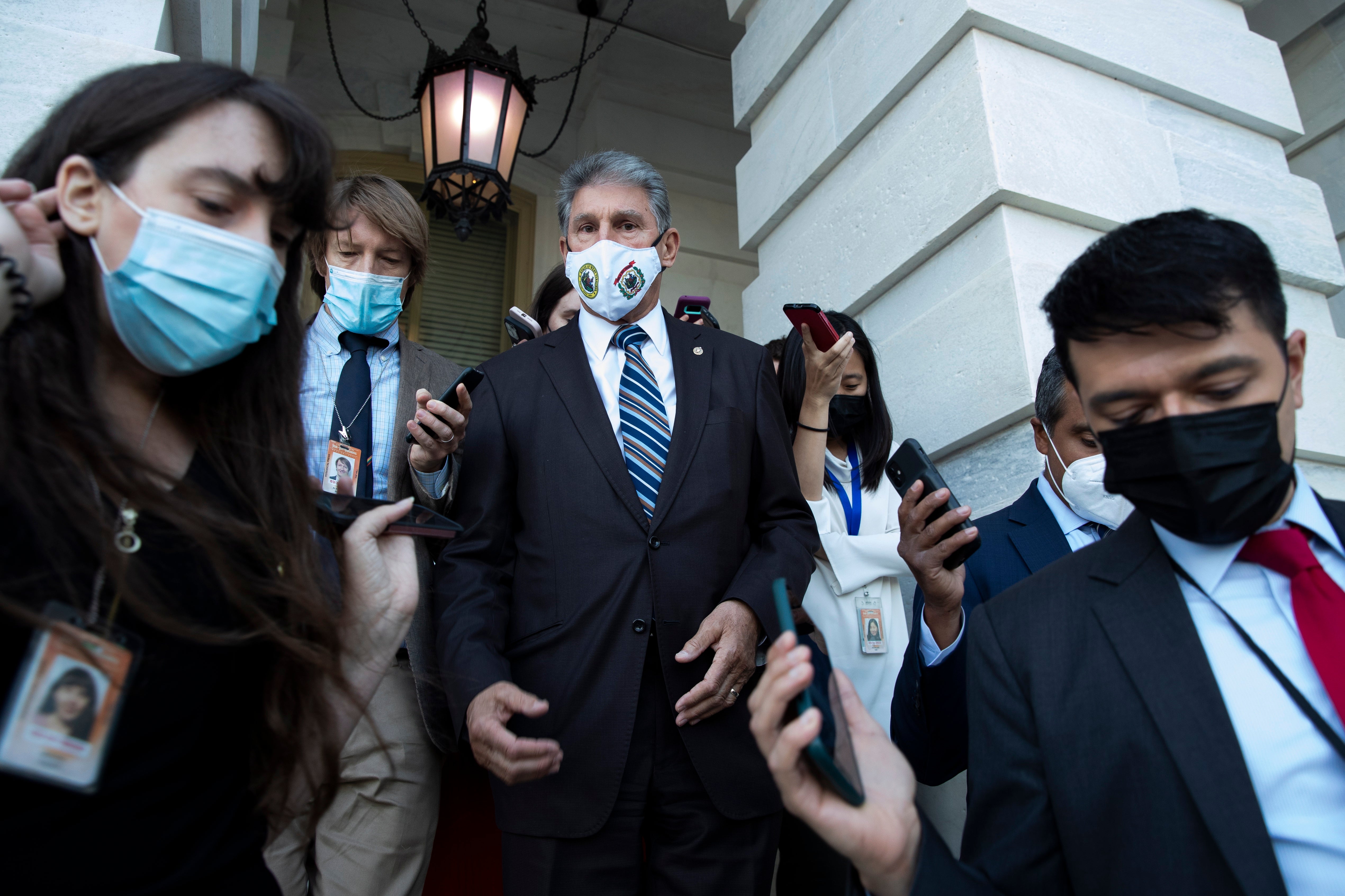 Democratic Senator from West Virginia Joe Manchin (C) is followed by members of the news media after leaving the Senate chamber during a procedural vote on raising the debt limit, on Capitol Hill in Washington, DC