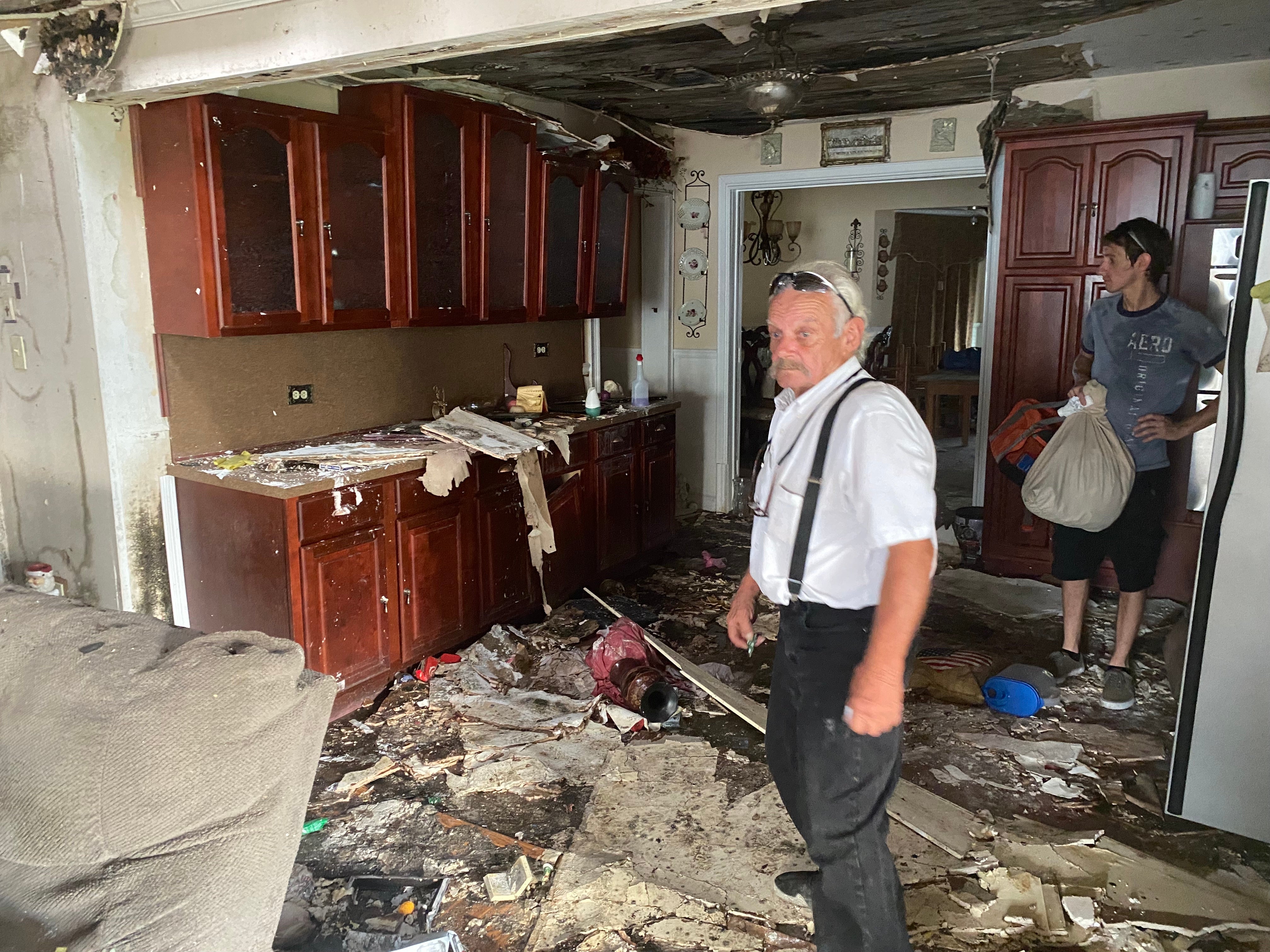 Durle Blanchard and his son Louis examine the damage inside his home in Chauvin, Louisiana nearly one month after Hurricane Ida.