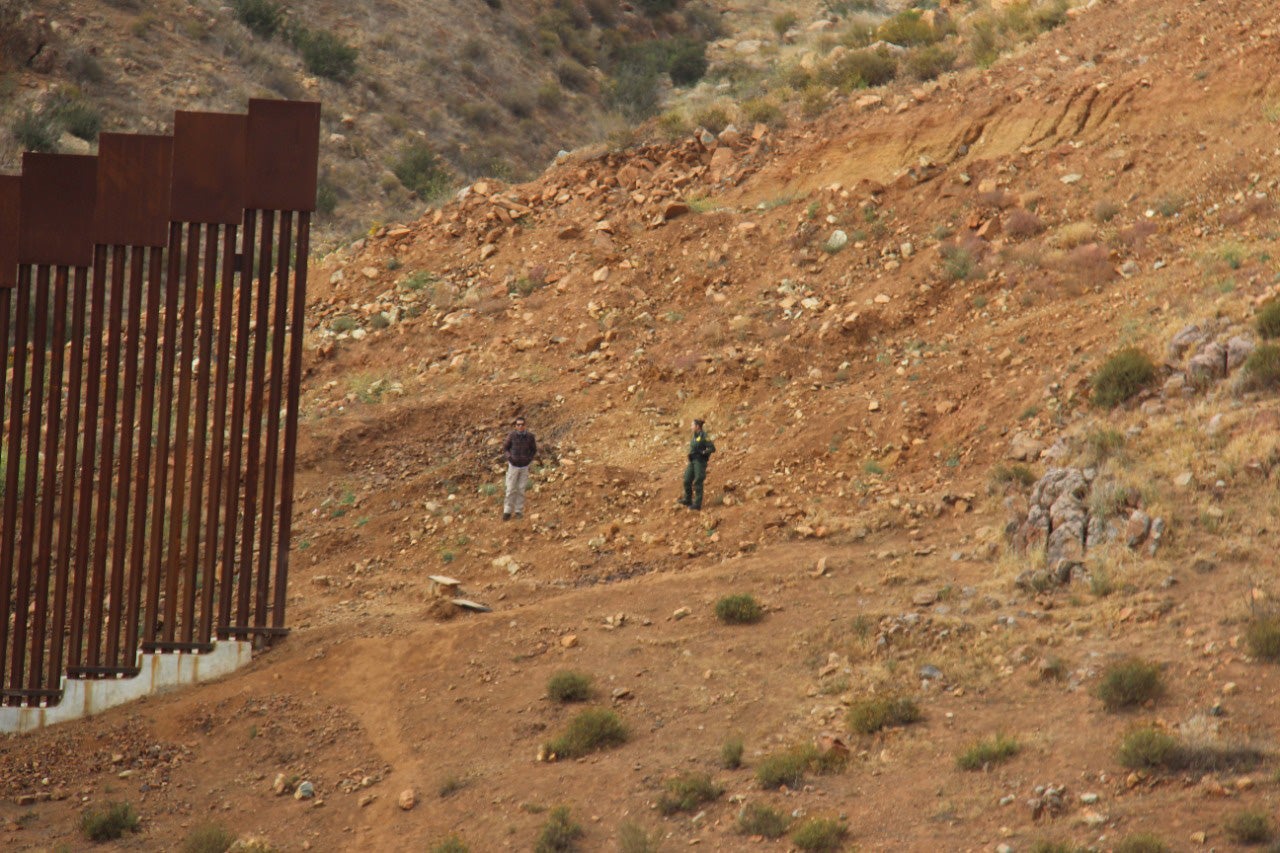 Officials speak in the gap at the US-Mexico border wall, on the outskirts of Tijuana, Mexico