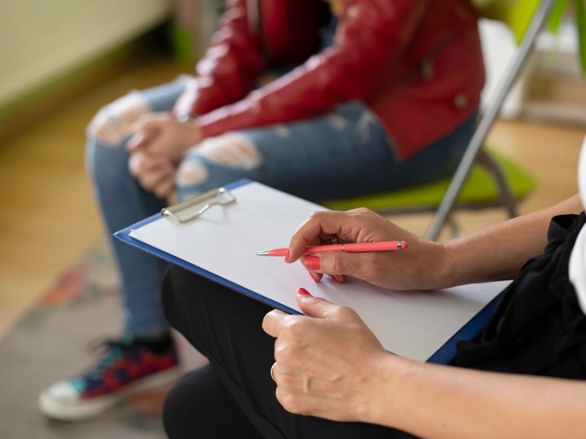 Close up of a therapists notes and a students knees during a mental health meeting