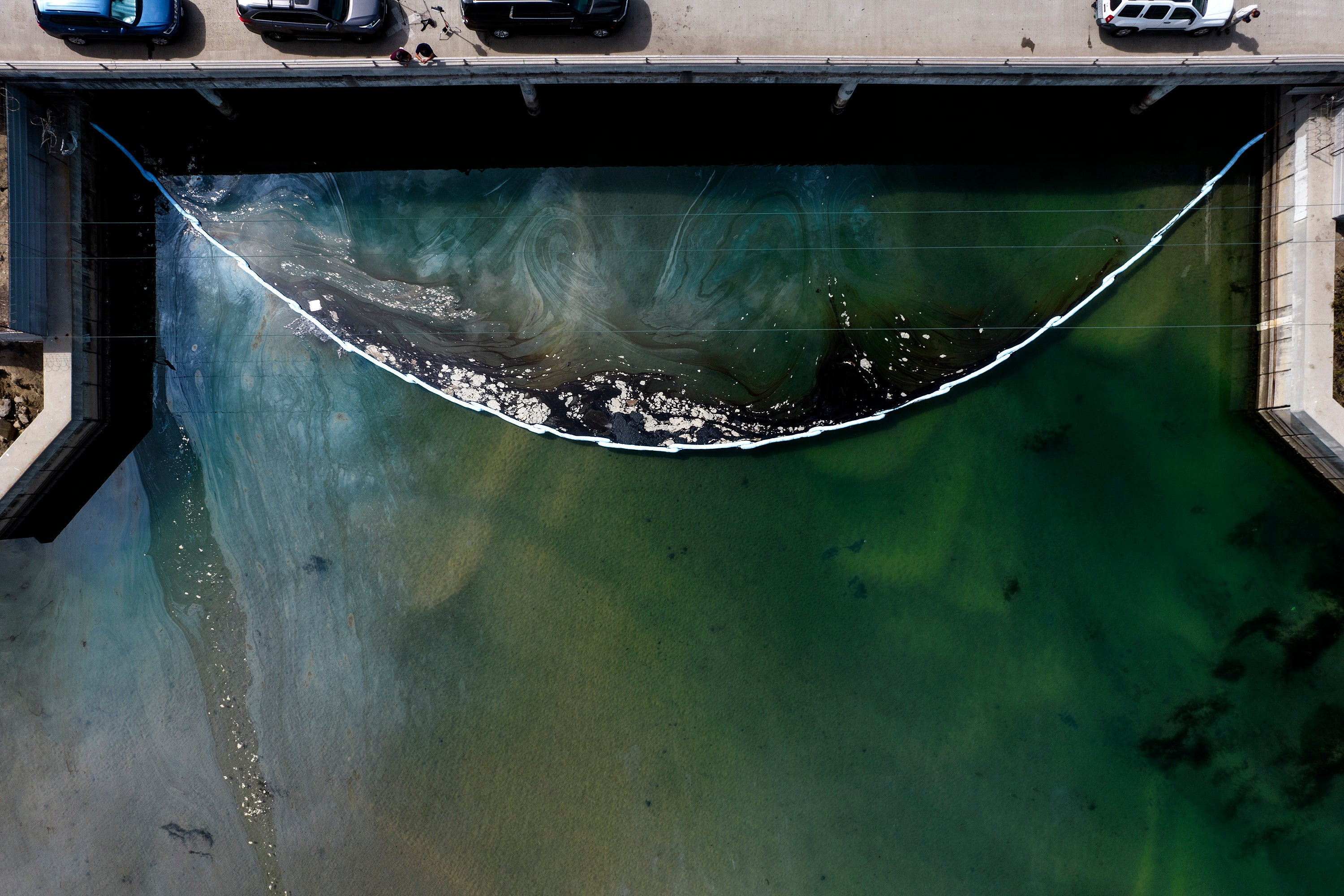 An aerial photo shows floating barriers known as booms set up to try to stop further incursion into the Wetlands Talbert Marsh after an oil spill in Huntington Beach, Calif., on Huntington Beach, Calif., on Monday, 4 October 2021.