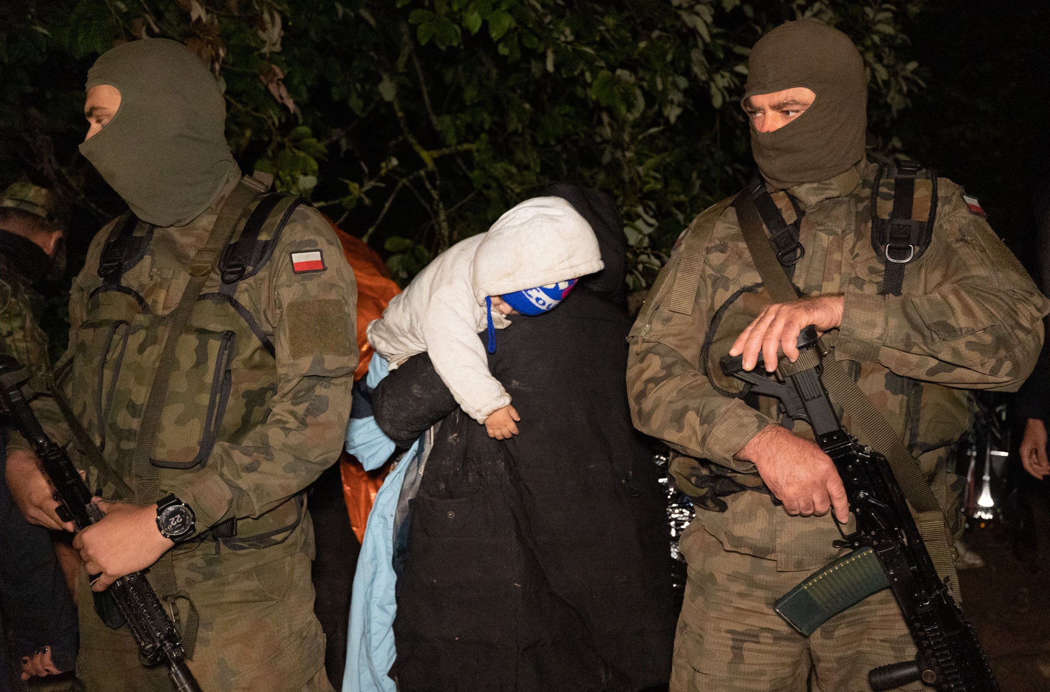 A family of asylum seekers are pictured next to Polish border guards in August