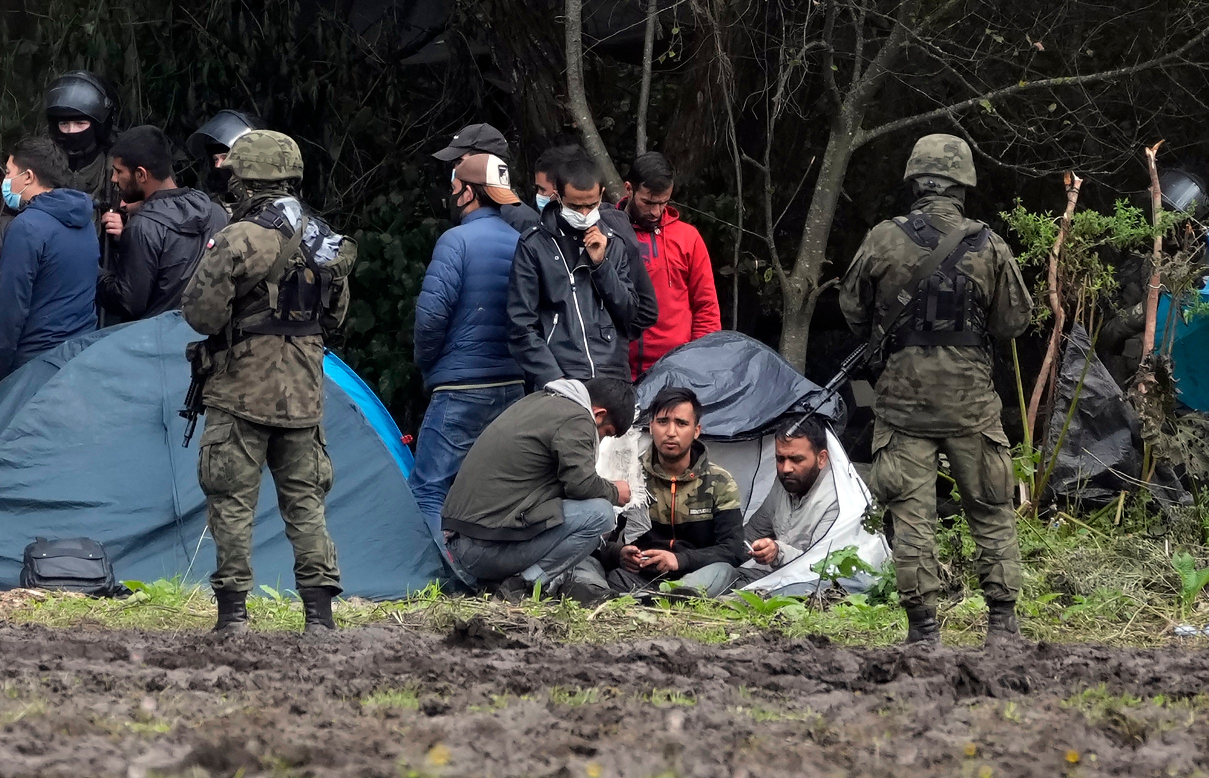 Migrants sit after crossing the border from Belarus in the village of Usnarz Gorny