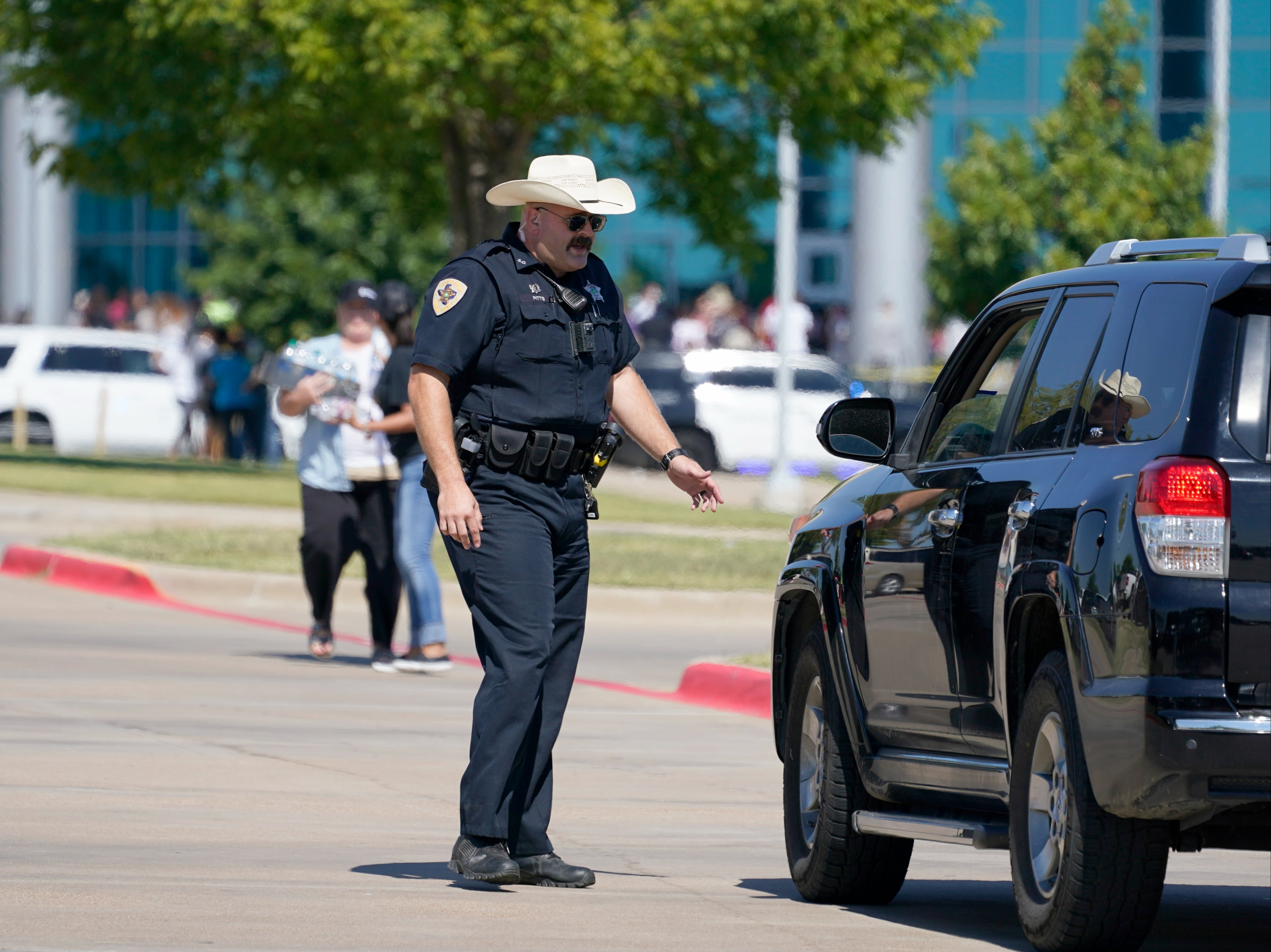 A law enforcement officer directs family members arriving at the Center For The Performing Arts to be reunited with their school children, Wednesday, Oct. 6, 2021