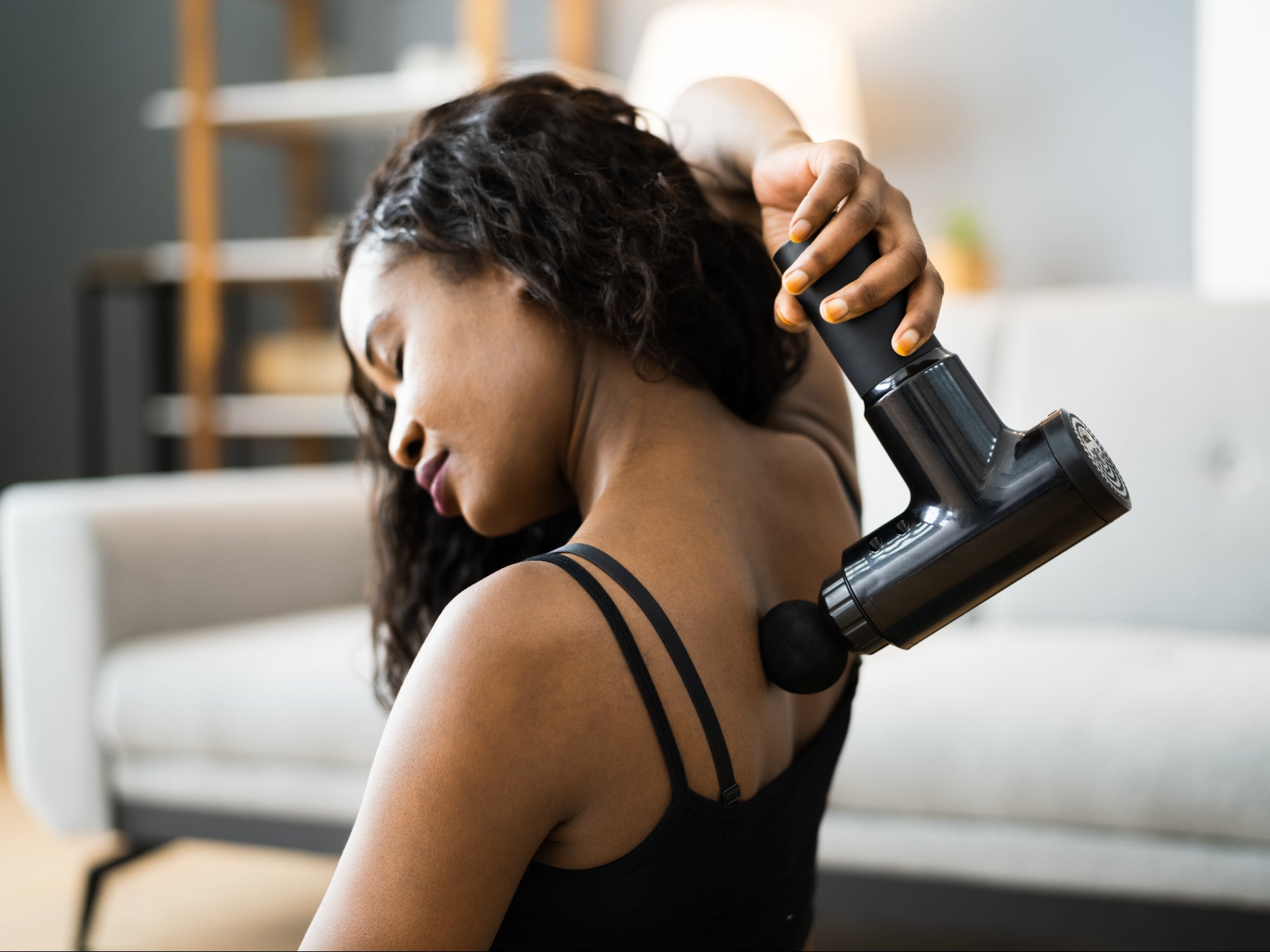 A woman uses a massage gun