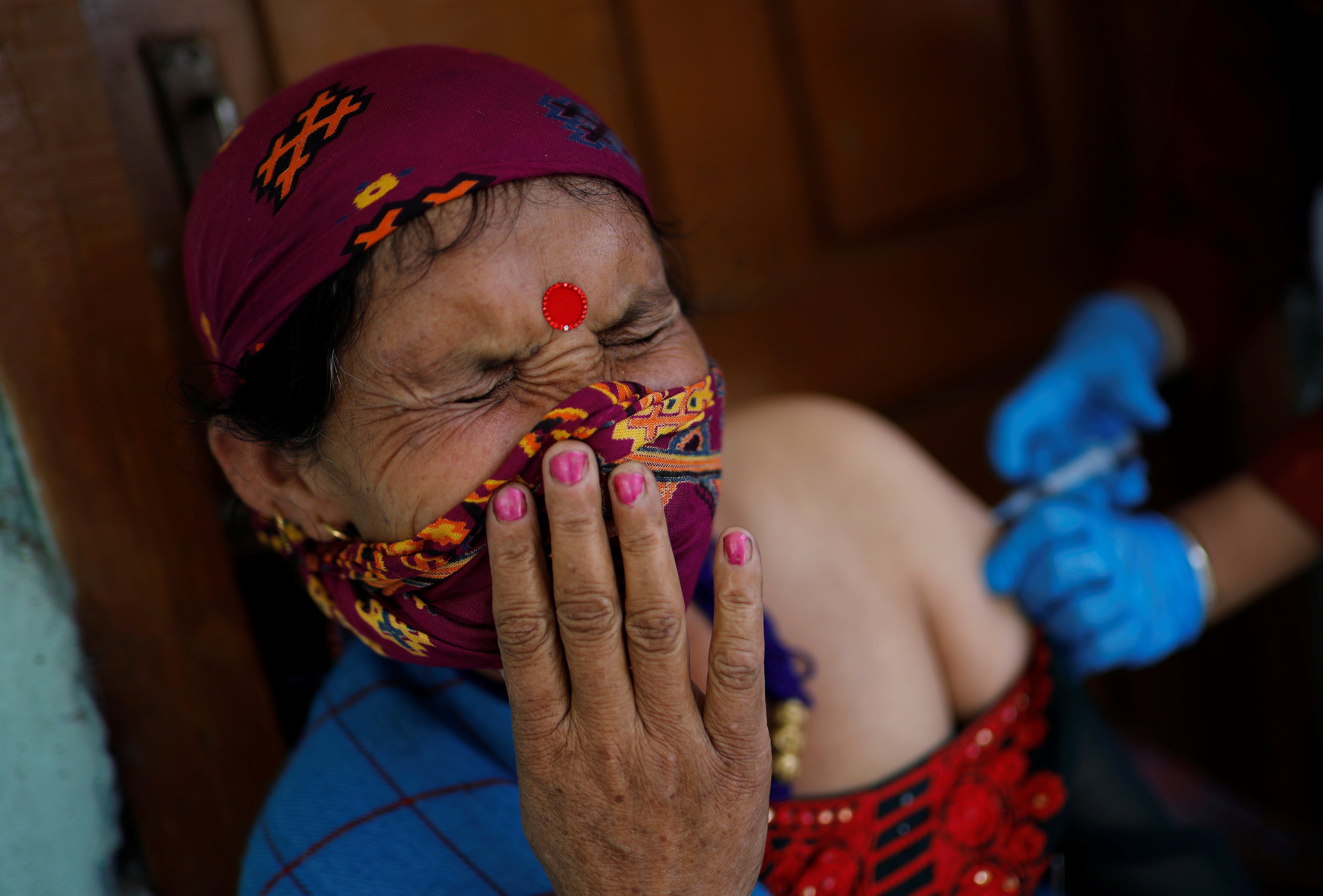 A villager grimaces as she receives a dose of the Covishield vaccine