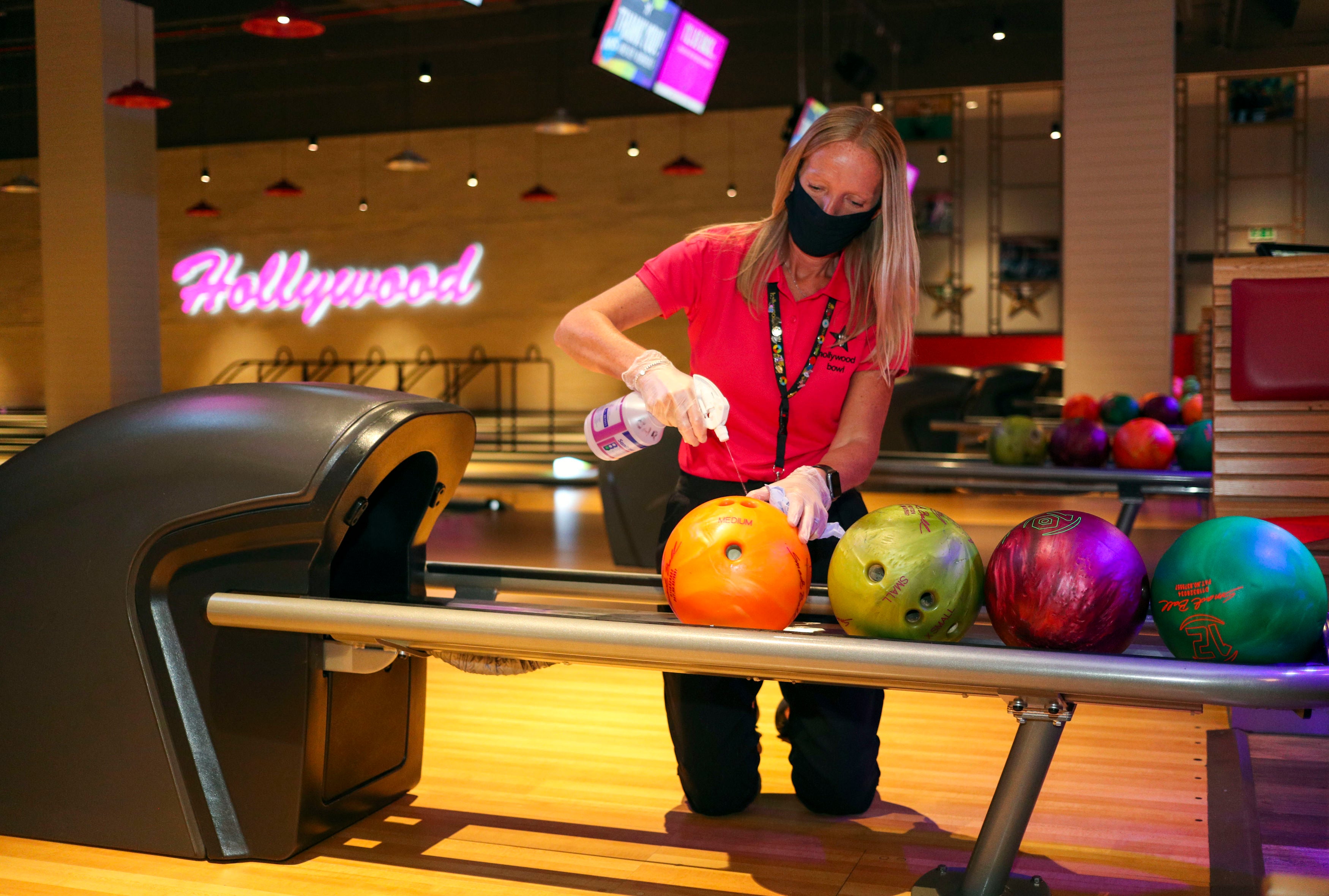 A member of staff at a Hollywood Bowl in Essex cleans the bowling balls (Steve Parsons/PA)