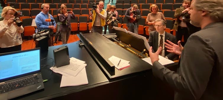 Journalists and musicians gather to hear a pianist play excerpts from the piece