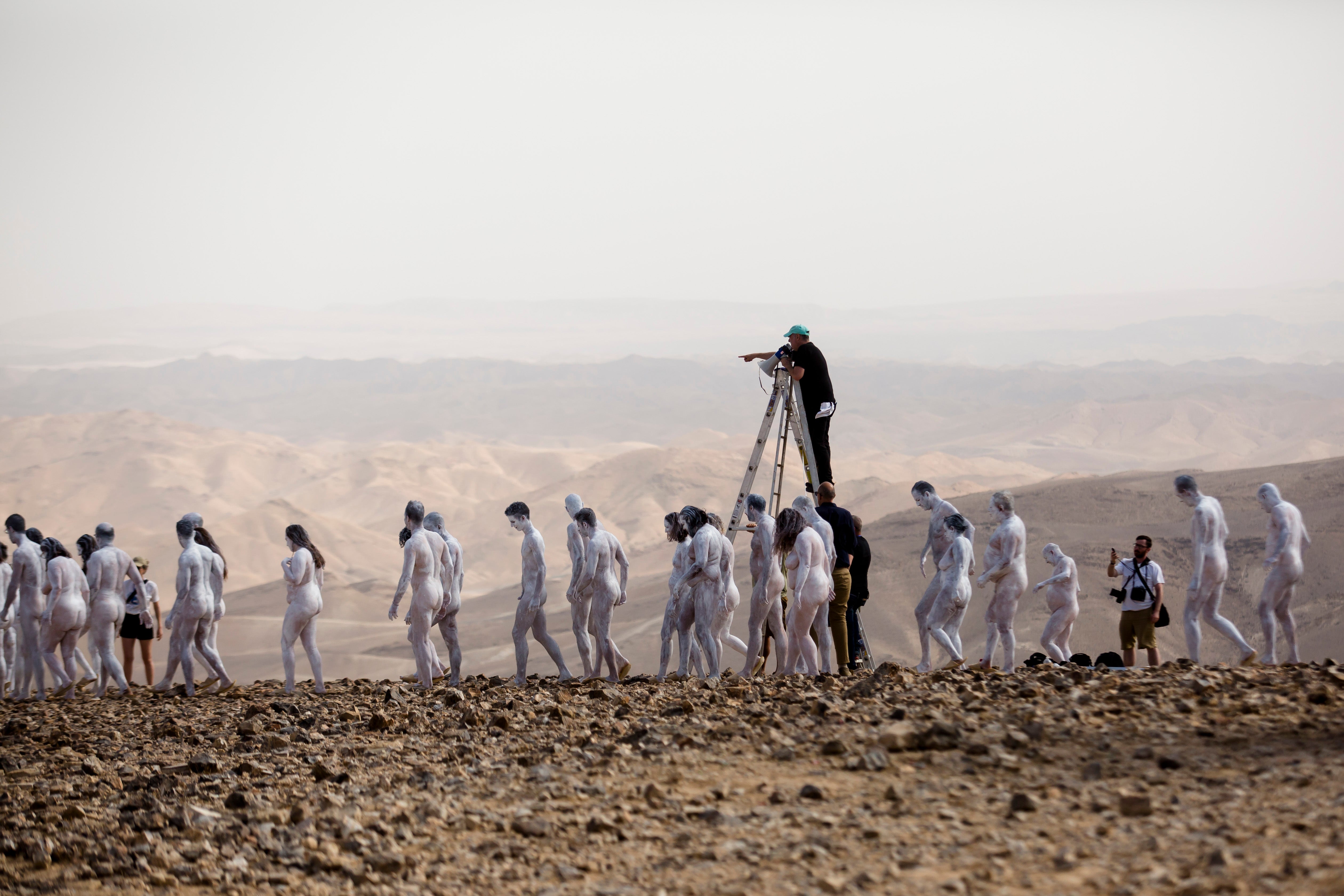 Nude models pose for a photograph as American artist Spencer Tunick stands on a ladder to give instructions to them