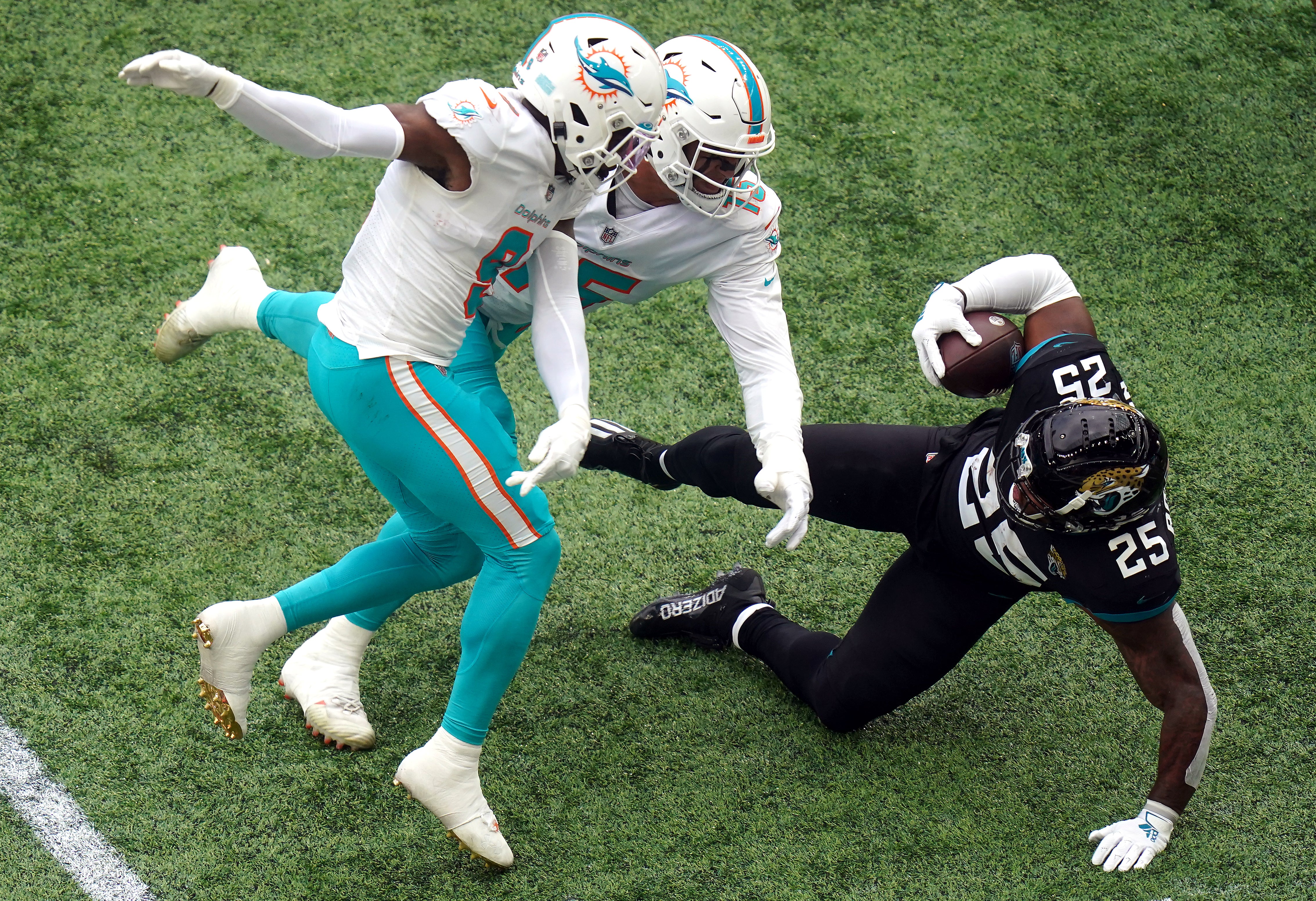 Jacksonville Jaguars’ James Robinson (right) is tackled by Miami Dolphins’ Noah Igbinoghene (left) and Jaelan Phillips during the match at Tottenham Hotspur Stadium