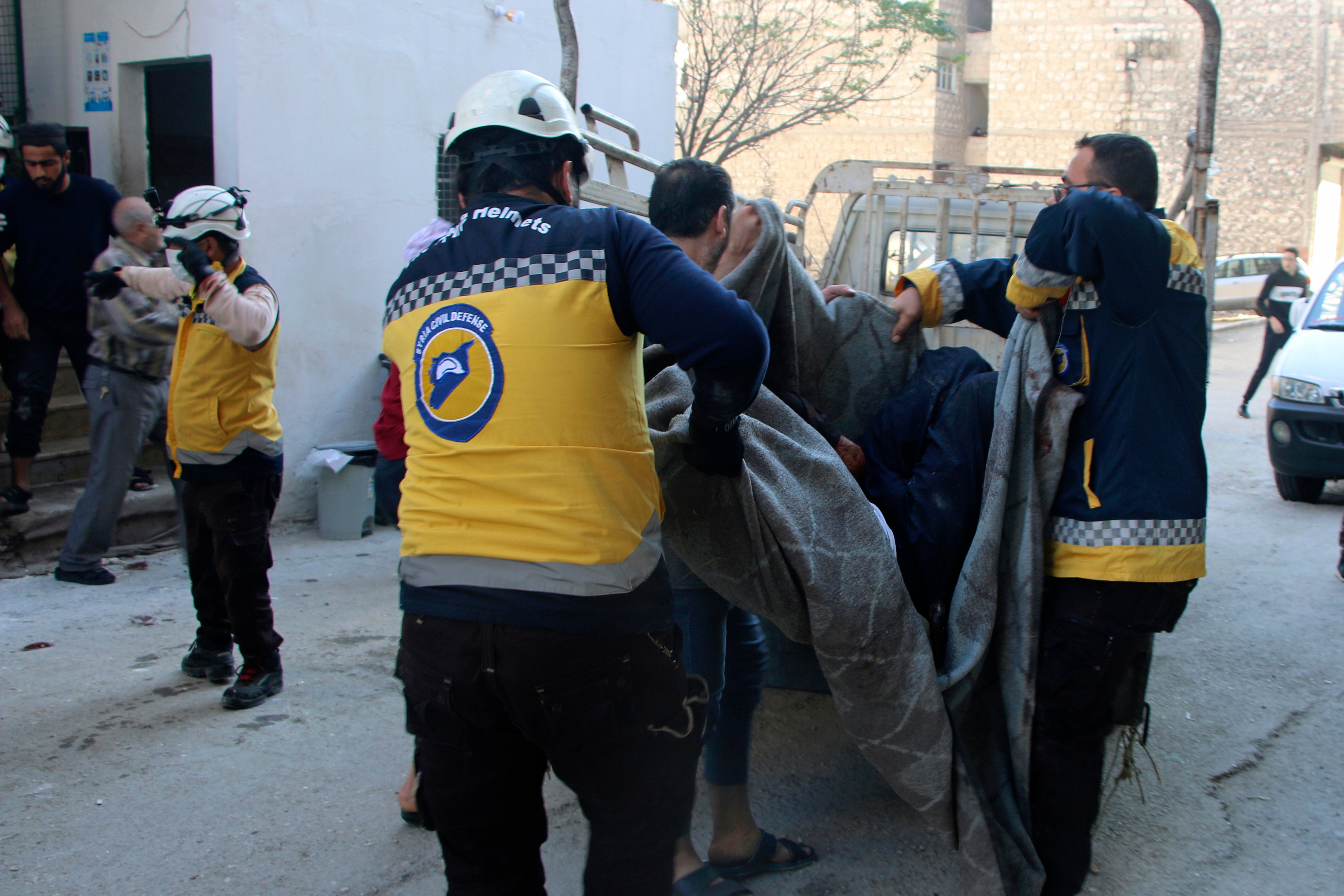 This photo provided by the Syrian Civil Defense White Helmets, which has been authenticated based on its contents and other AP reporting, shows Syrian White Helmet civil defense workers carrying a casualty, in the northern town of Ariha, in Idlib province, Syria, Wednesday, Oct. 20, 2021