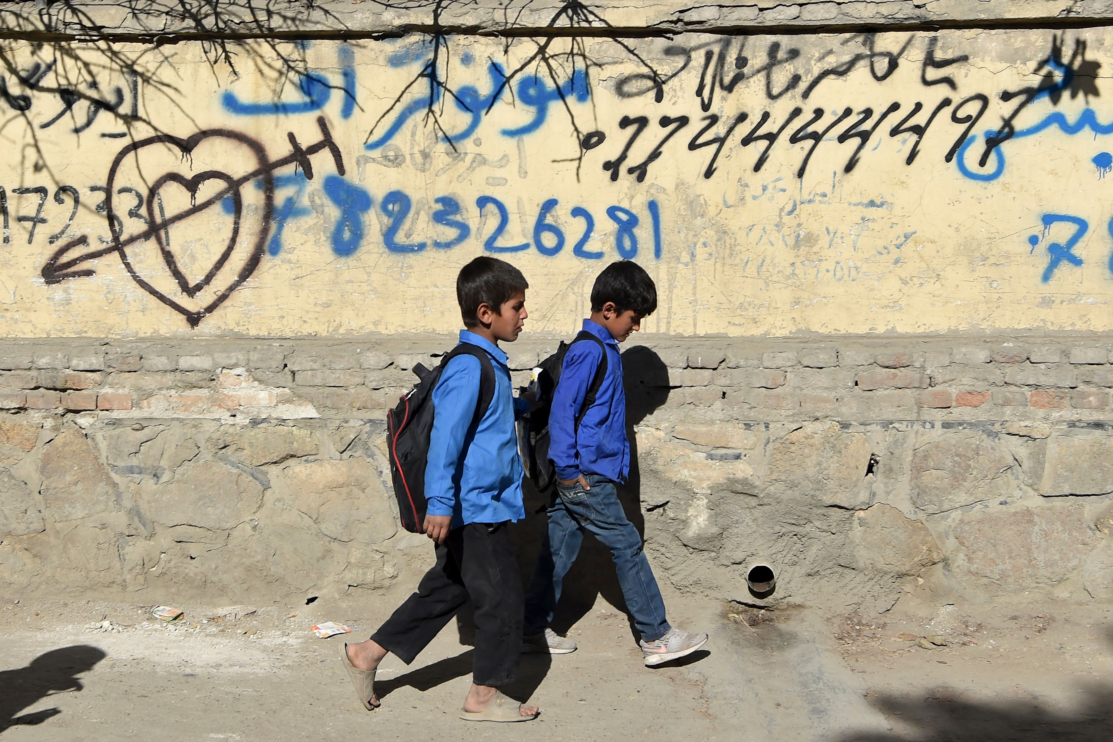 Children walk home after attending school along a roadside in Kabul, October 2021