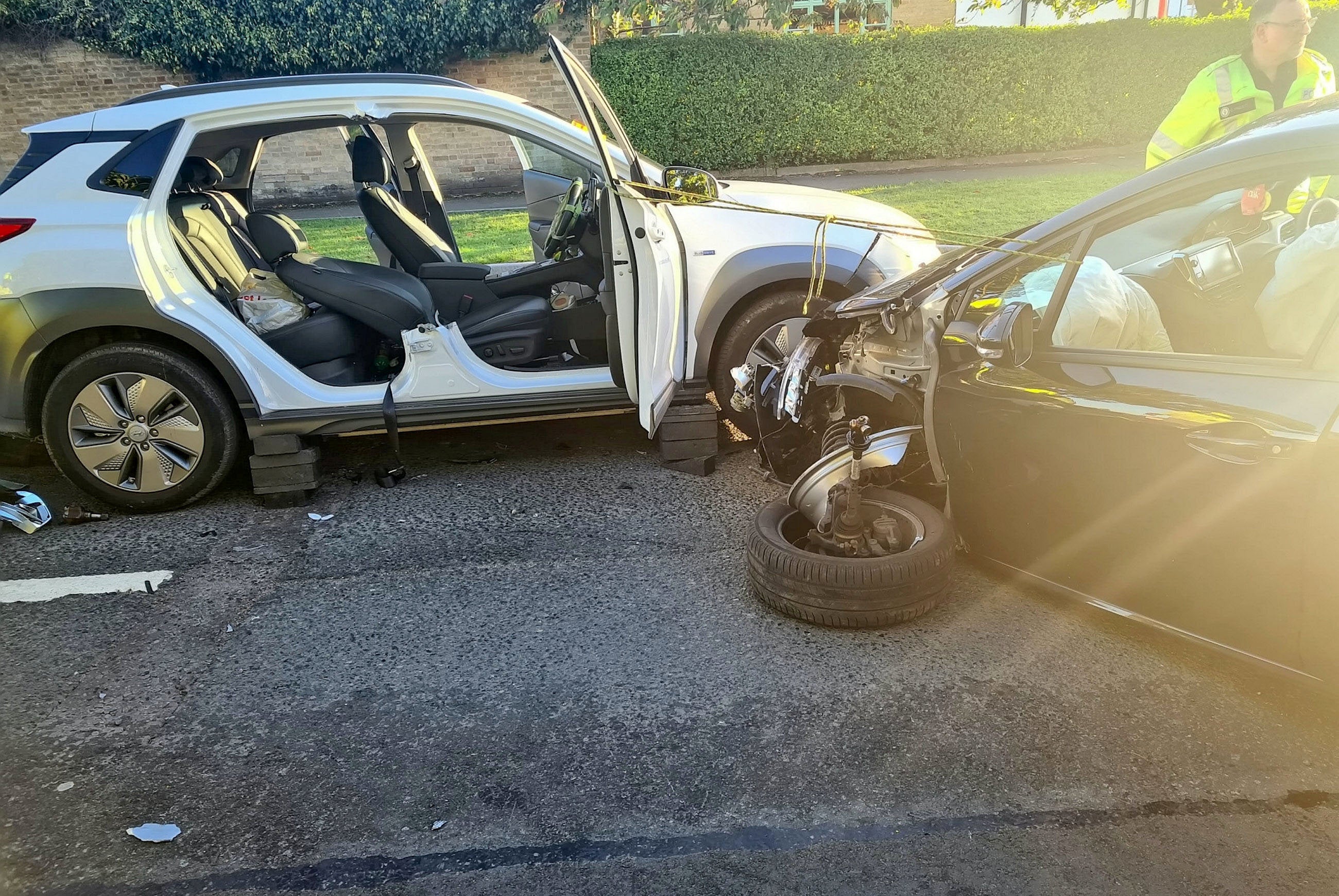 Images from the scene show a severely damaged black car positioned diagonally across the road