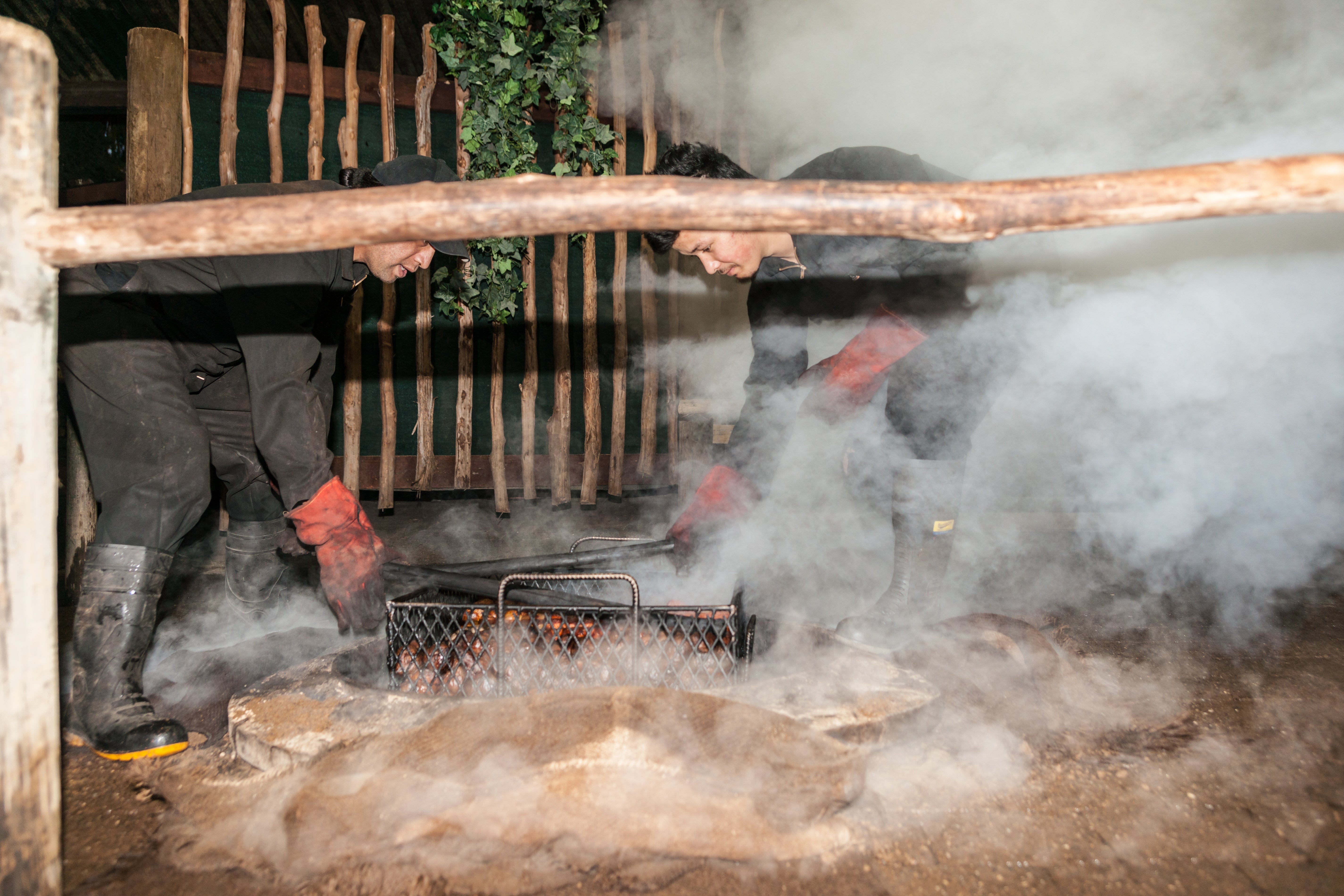 Smoke and dust fly as food is prepared for a traditional Maori feast by hāngi, steaming through heat from underground thermal activity or heated stones in the base of a pit