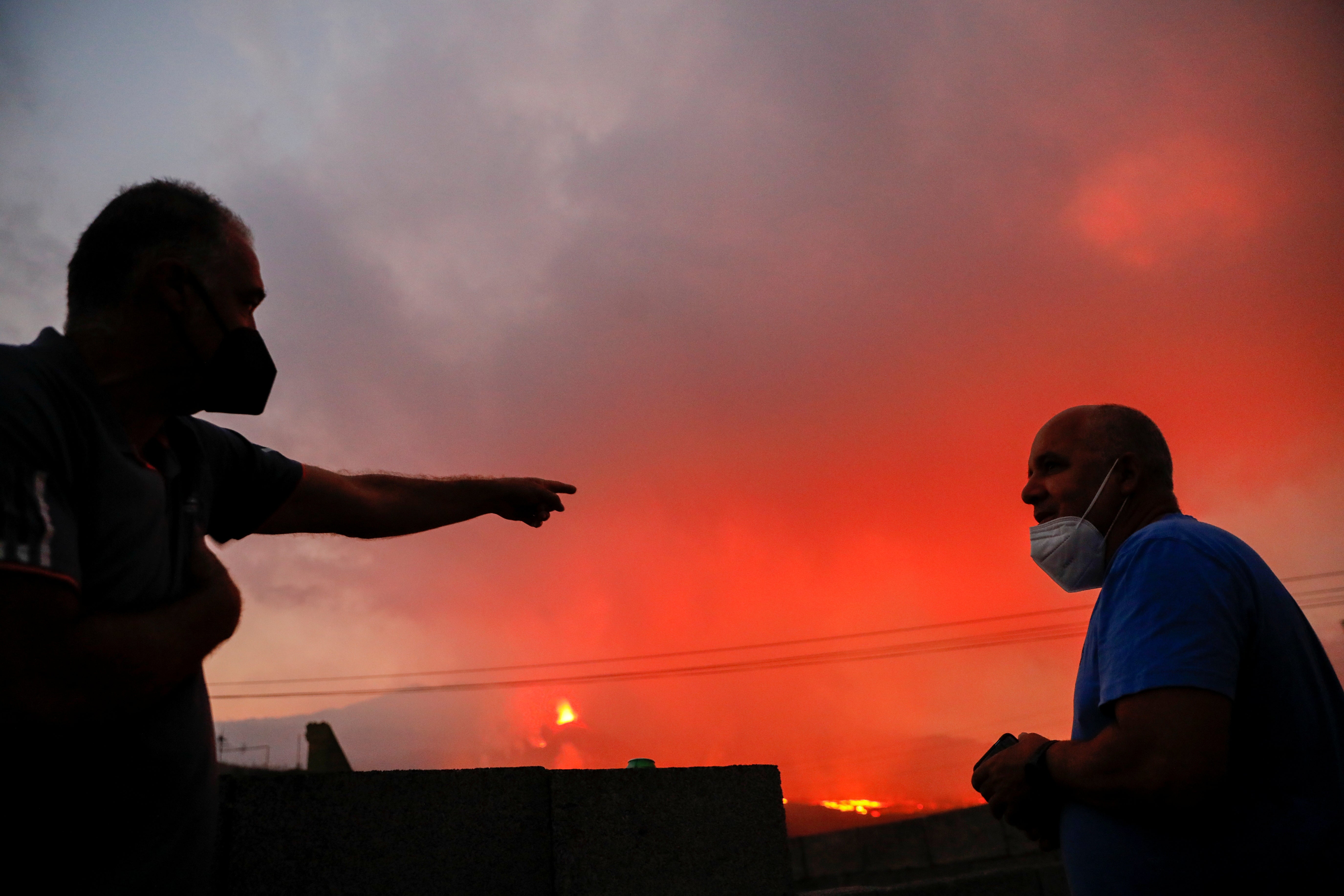 Two men that were evacuated from their homes a month ago talk as they look at the Cumbre Vieja volcano