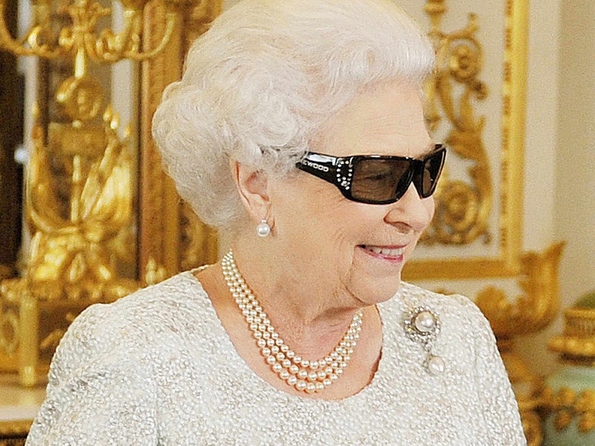 Queen Elizabeth watches a preview of her Christmas message wearing a pair of 3D glasses, studded with Swarovski crystals in the form of a "Q", at Buckingham Palace in central London, 2012