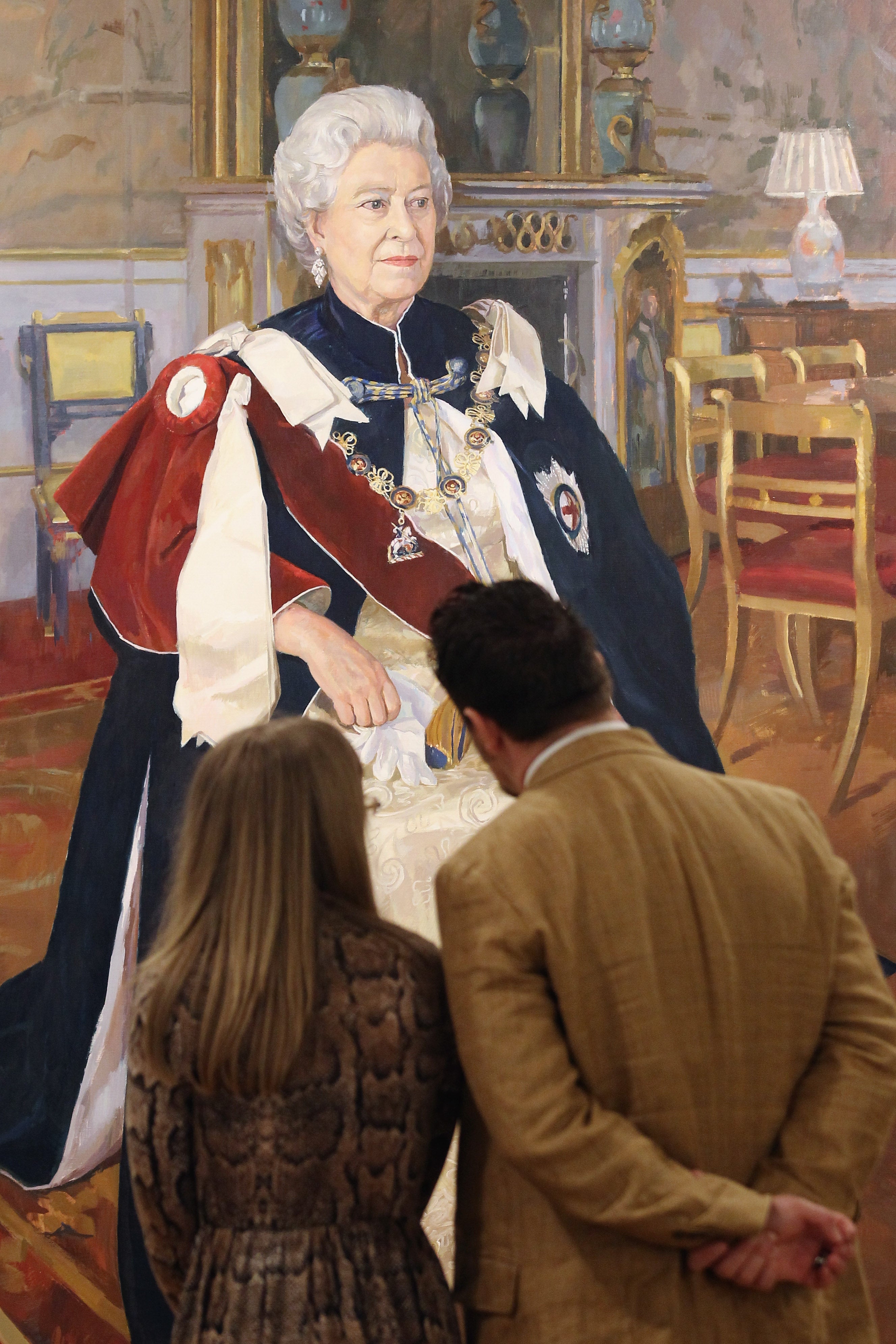 Visitors look at a painting of Queen Elizabeth II during a photocall for the Royal Society of Portrait Painters exhibition at the Mall Galleries on May 2, 2012 in London