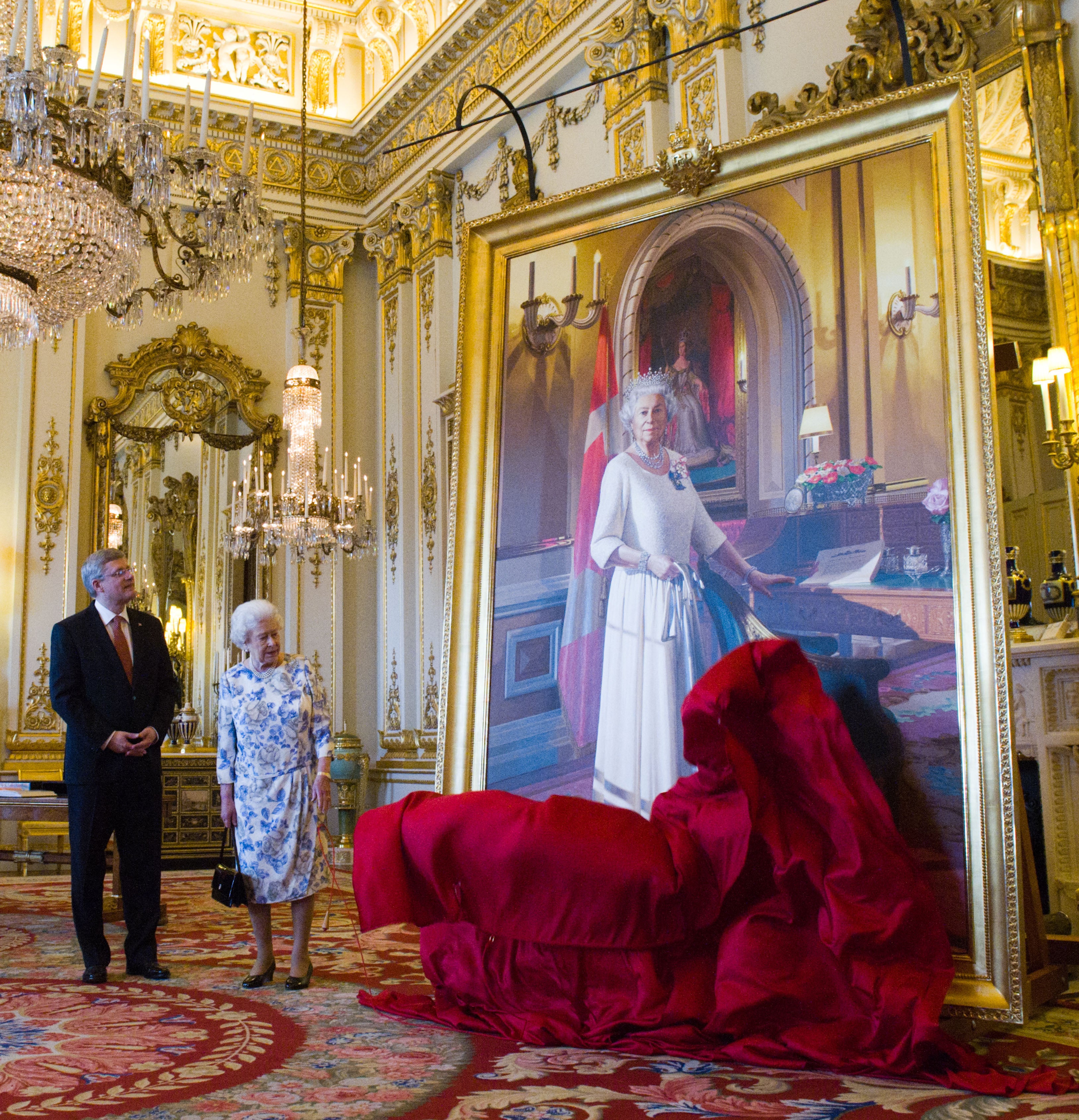 Canadian Prime Minister Stephen Harper stands with Queen Elizabeth II as she unveils a portrait of herself in the White Drawing Room at Buckingham Palace on June 6, 2012 in London