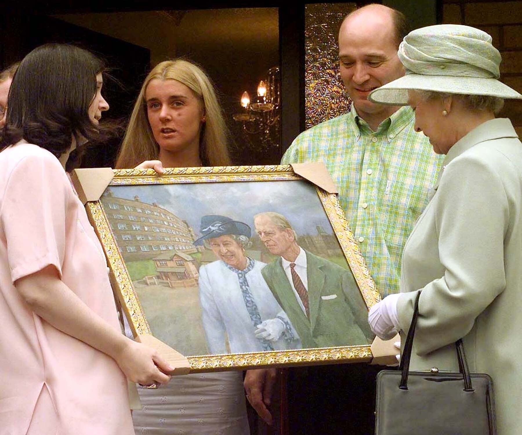 The Queen receives a painting of her visit with the Duke of Edinburgh to St. Andrews Gardens Estate in Liverpool presented by Brenda Prendergast and her husband Charles after she visited their home