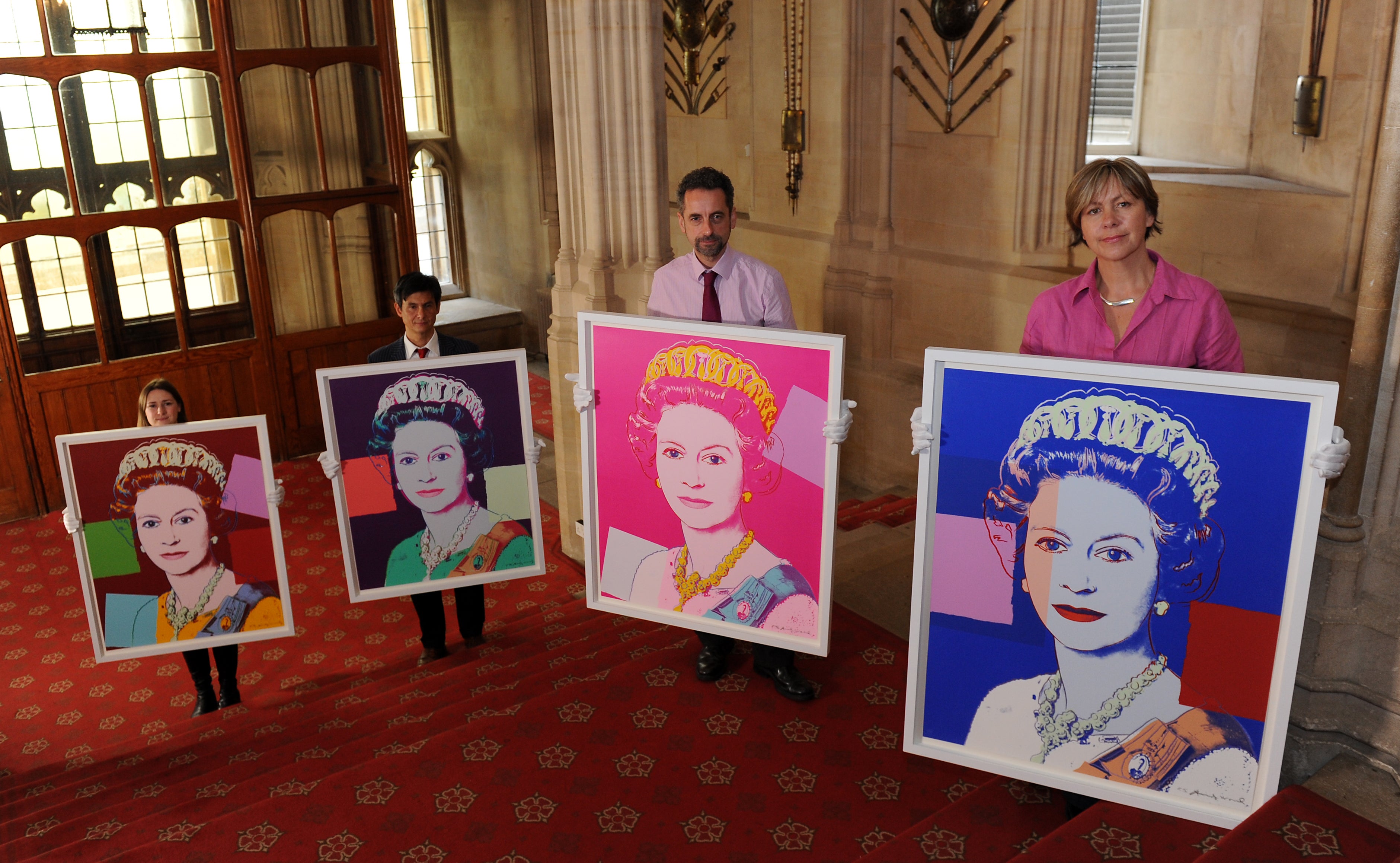 Exhibition curator Lauren Porter (left), Allan Chinn, Martin Clayton (second right) and Kate Stone (right) pose with Andy Warhol’s Reigning Queens: Queen Elizabeth II portraits on the staircase leading to the Viewings Gallery at Windsor Castle