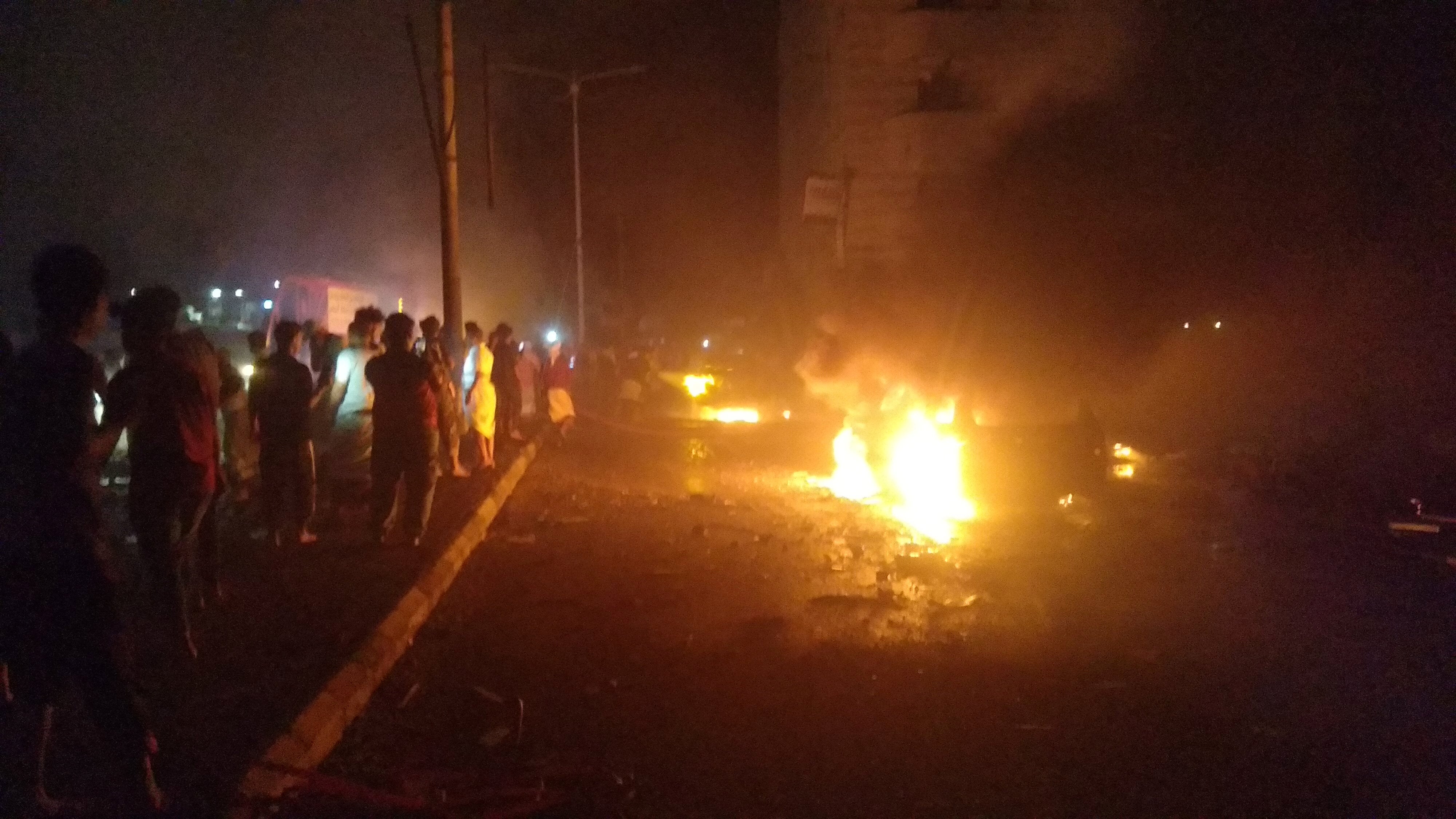 Bystanders watch as cars burn at the site of an explosion outside Aden international airport in Yemen on Saturday