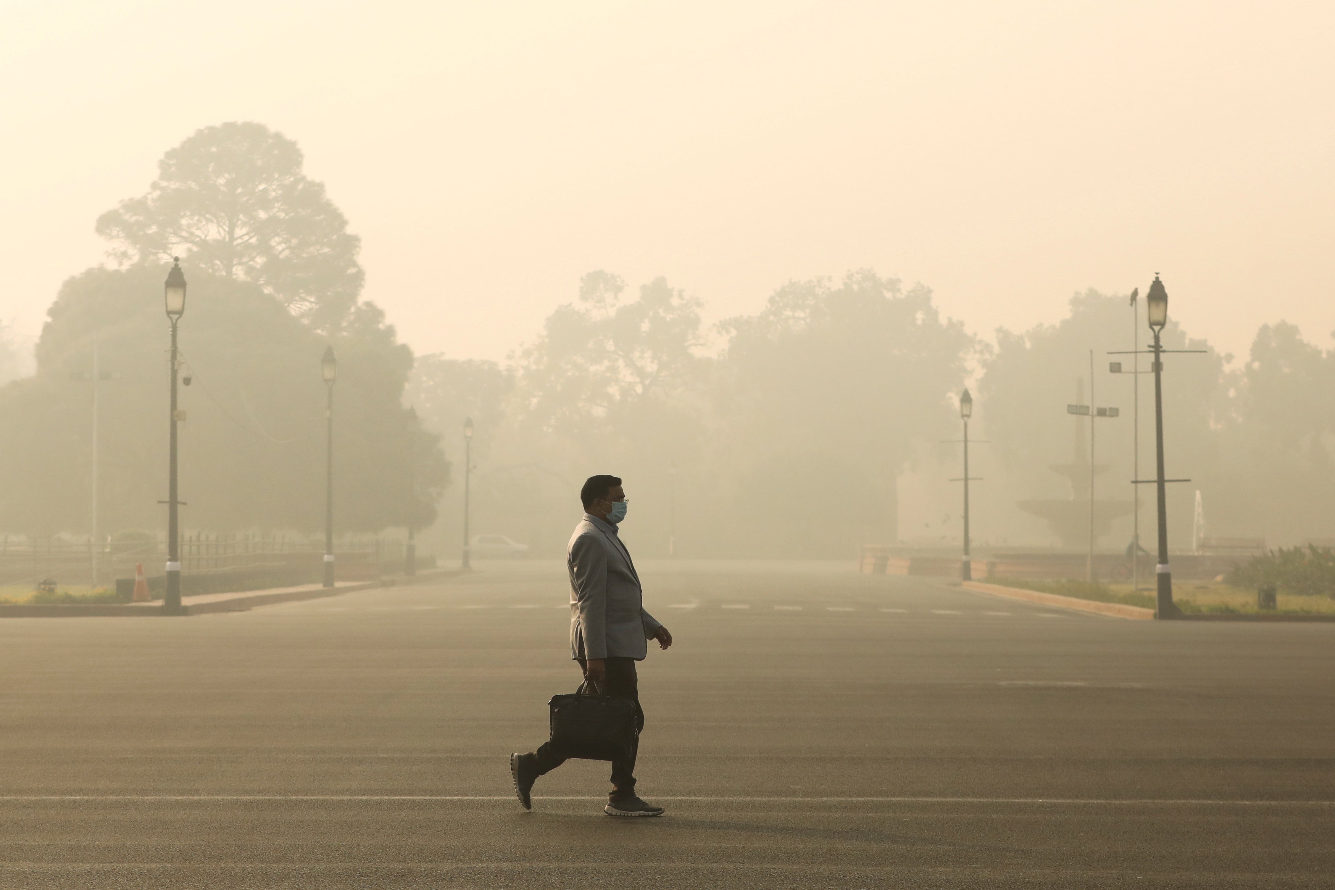 A man walks along a road on a smoggy morning in New Delhi