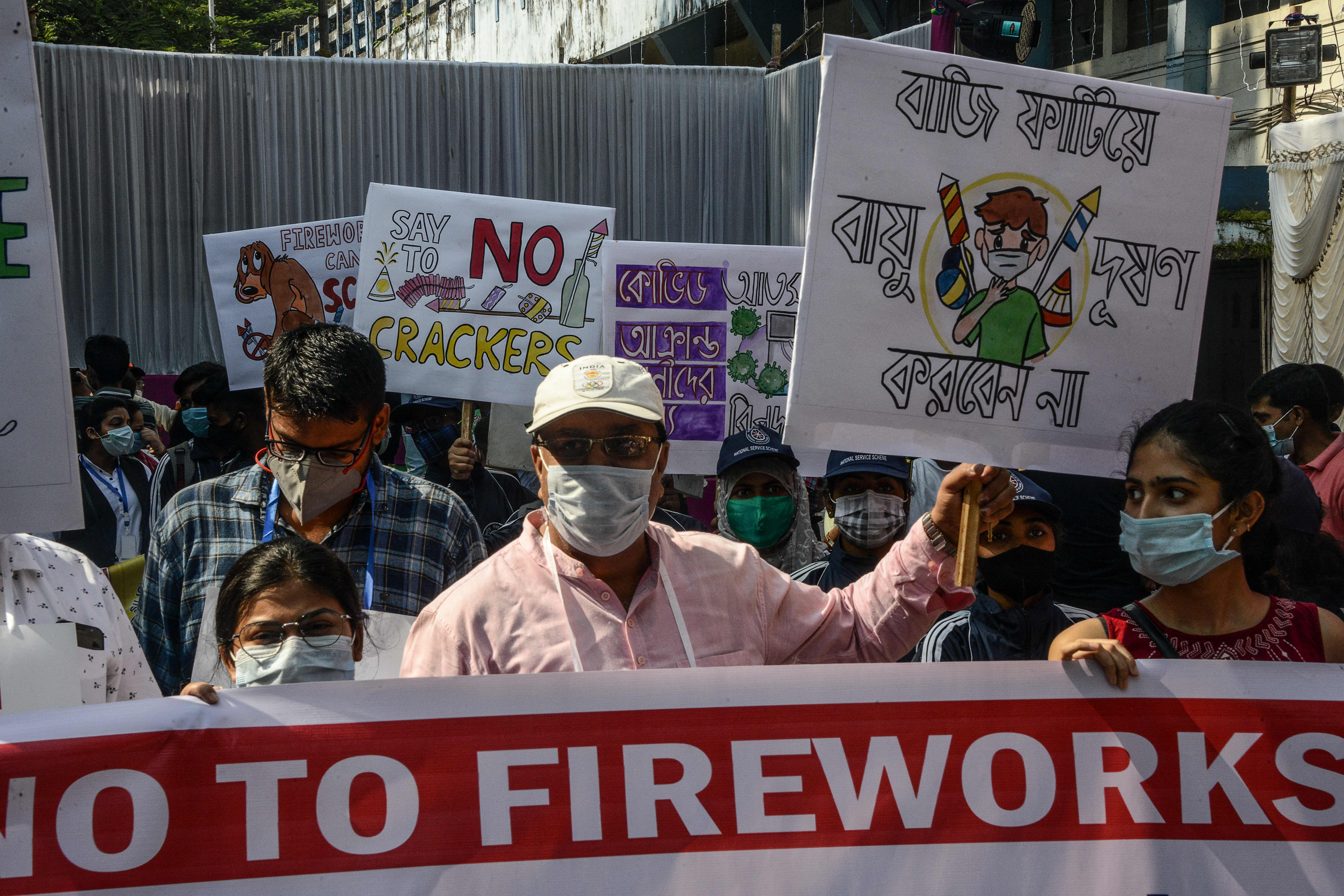 People hold placards to raise awareness on air pollution caused by firecrackers used during the celebrations for the upcoming Hindu festival of Diwali