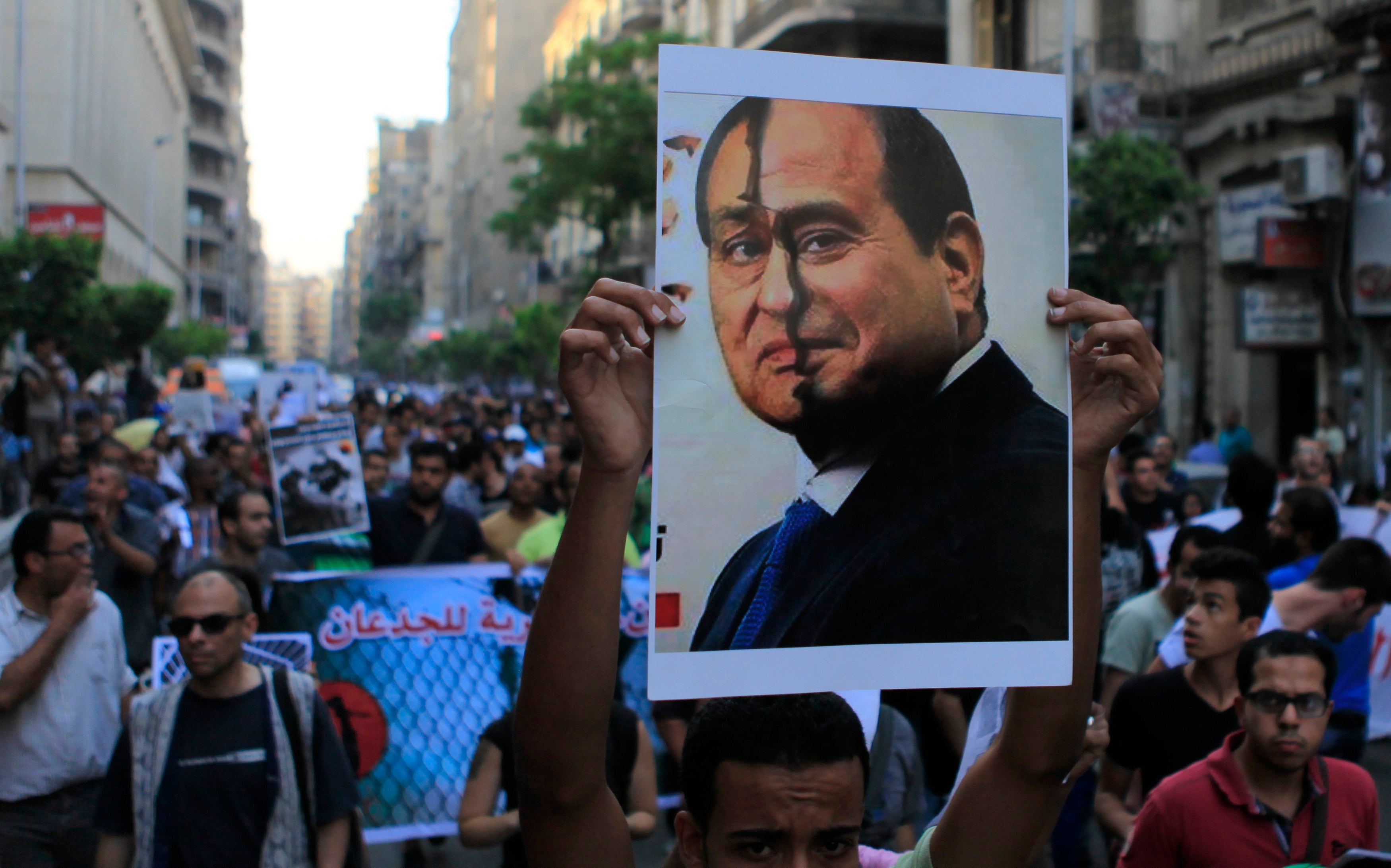 A protester shows a placard with the faces of Hosni Mubarak and Abdel Fattah al-Sis