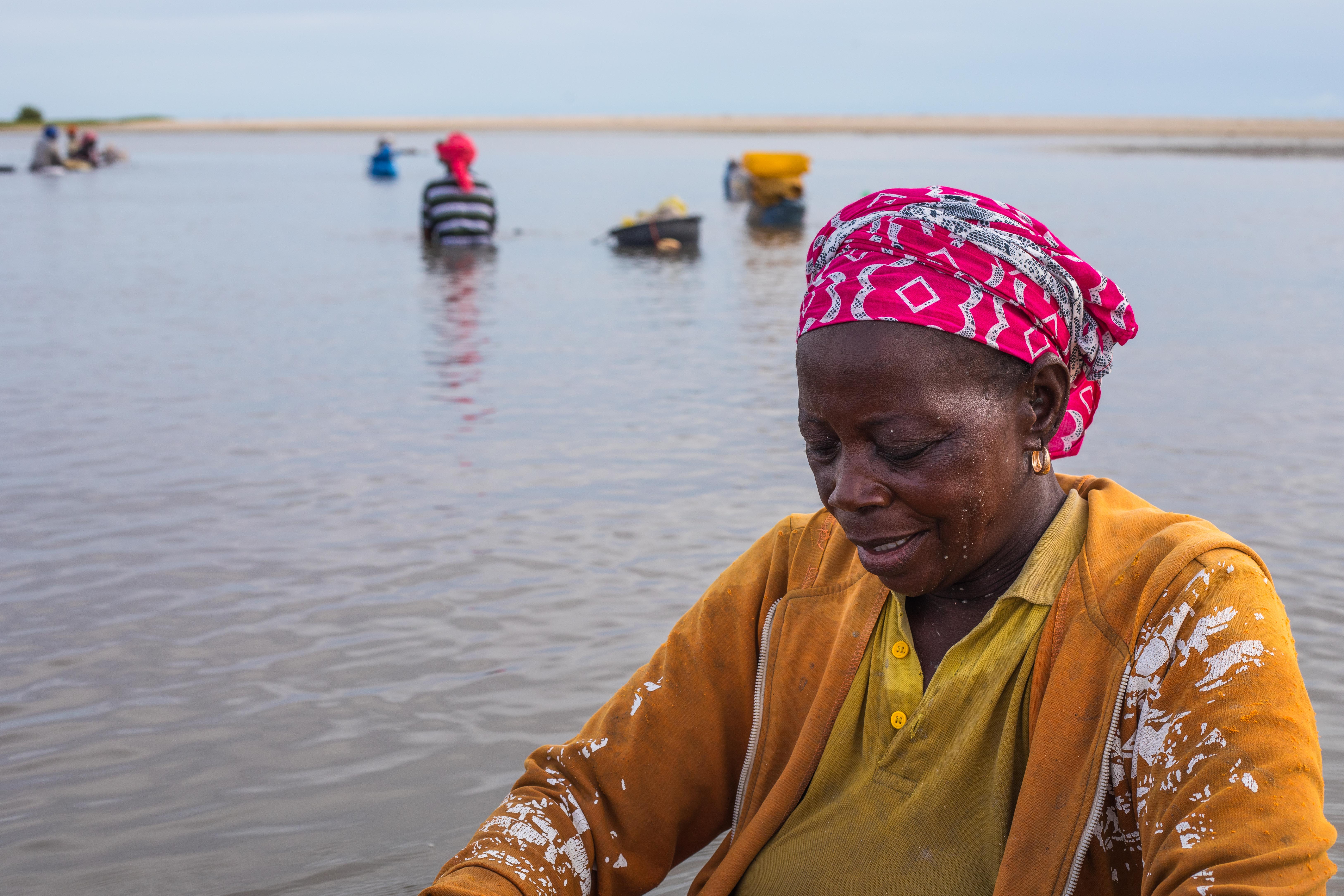 A woman gathers cockles from the mangroves in Joal-Fadiouth