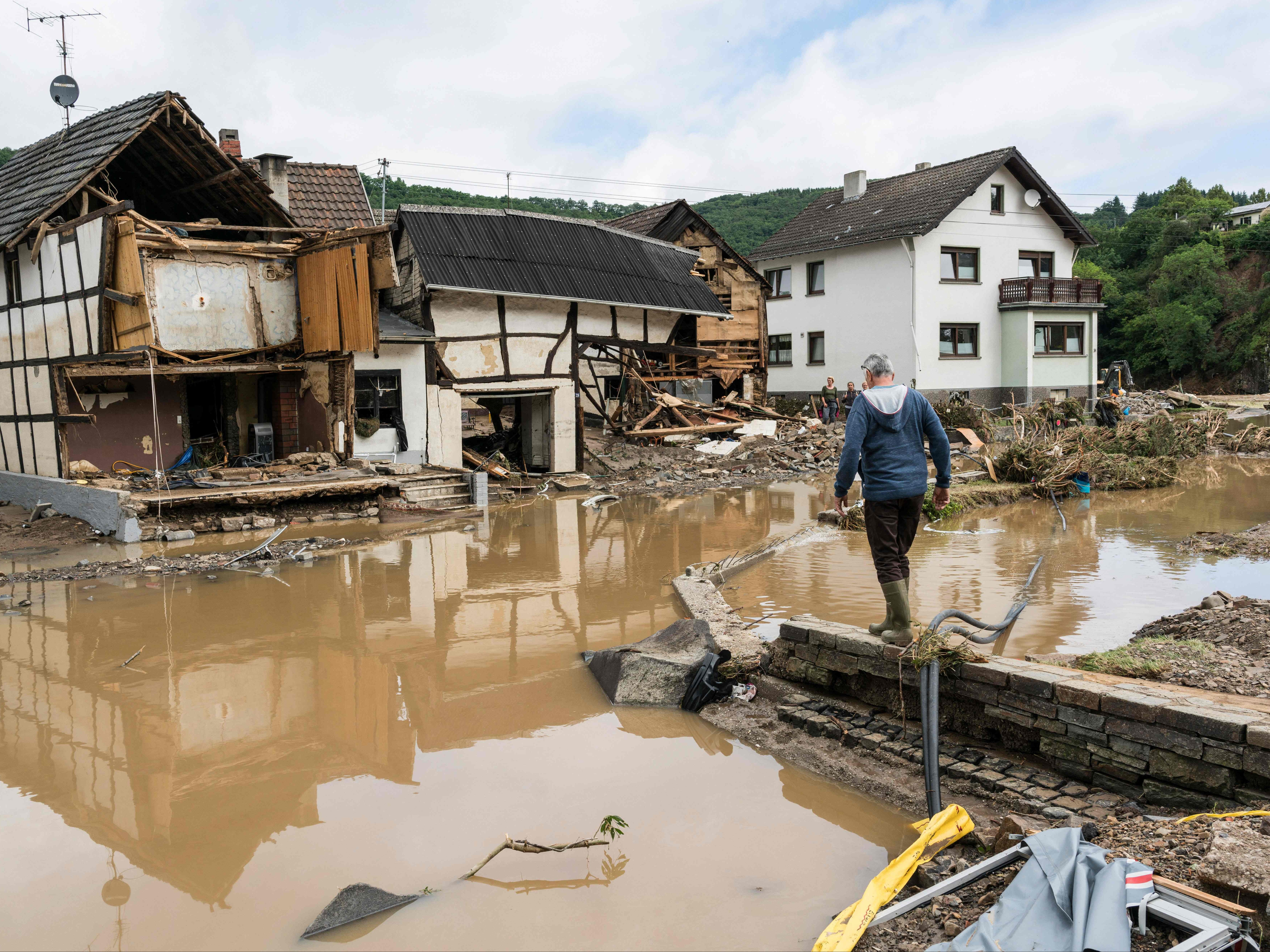 A man walks through floods towards destroyed houses in Schuld, western Germany, in July