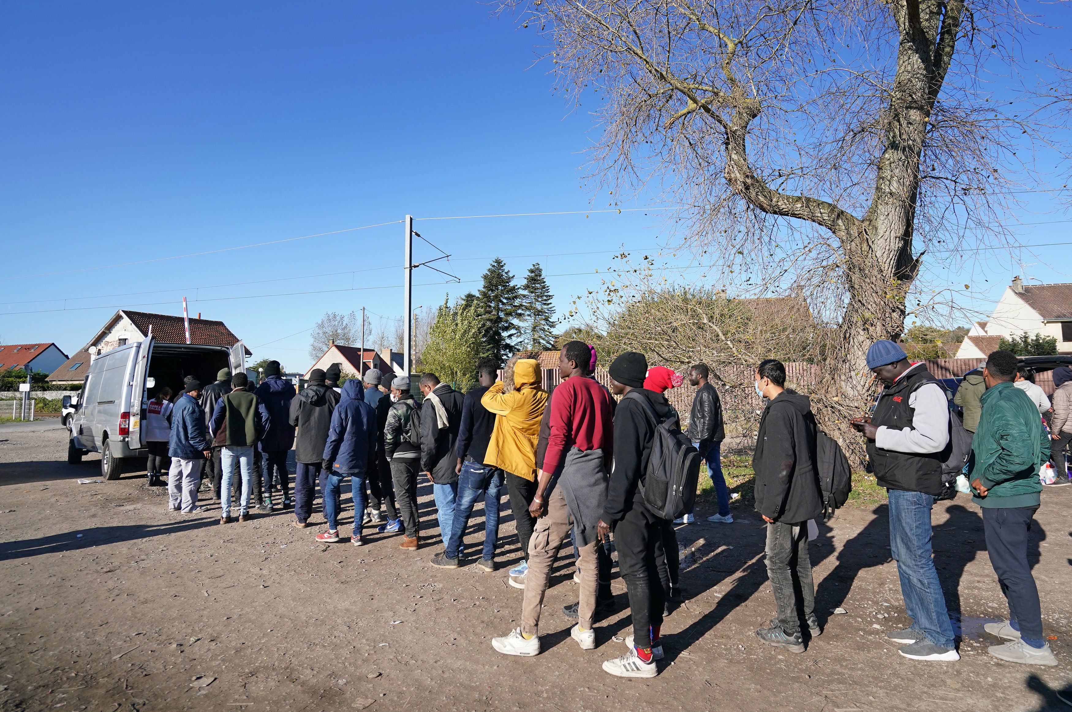 Migrants queue for food at a makeshift camp in Calais