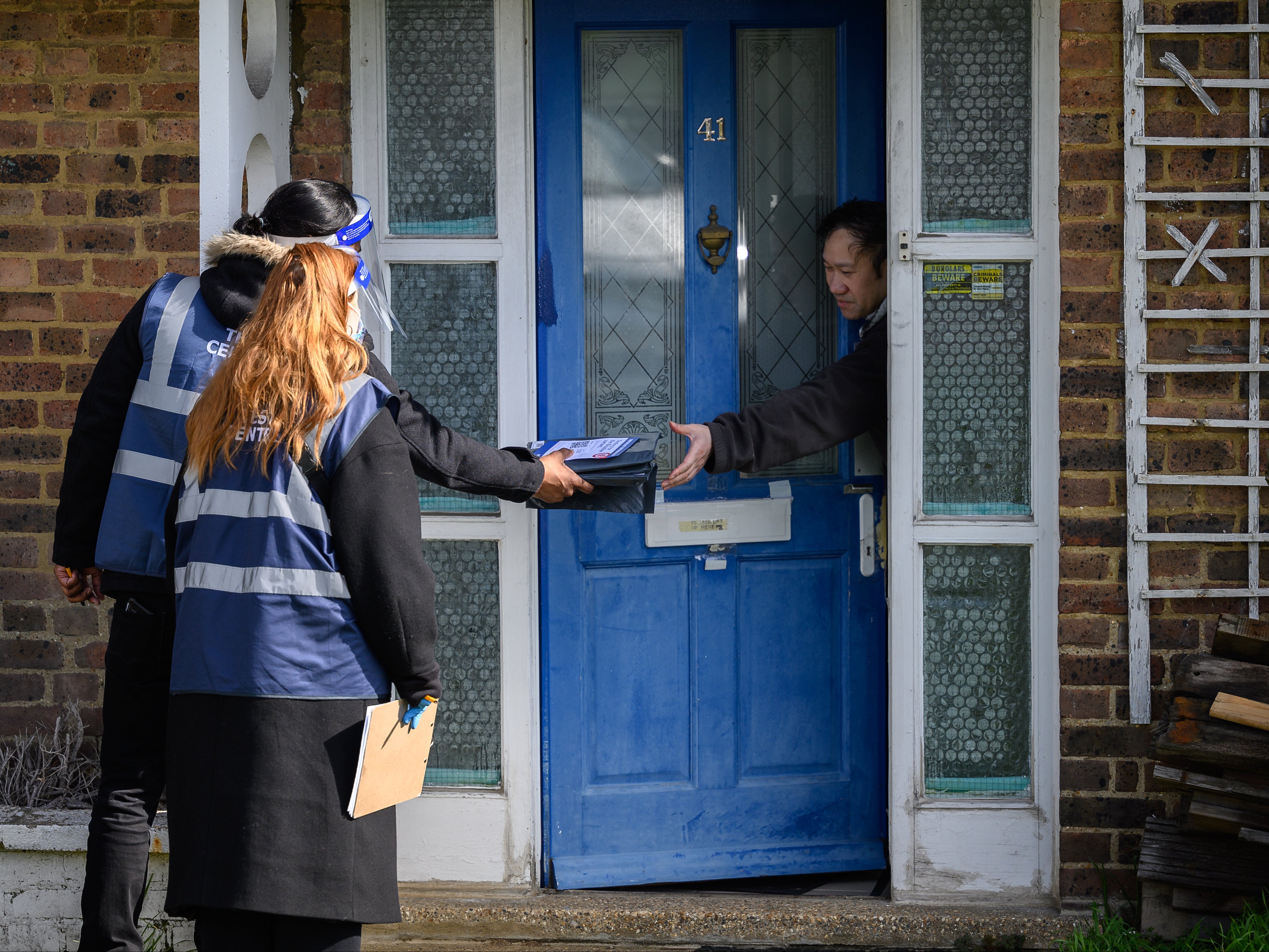 A man receives a kit from volunteers as they deliver Covid-19 test kits to the doors of residents in London