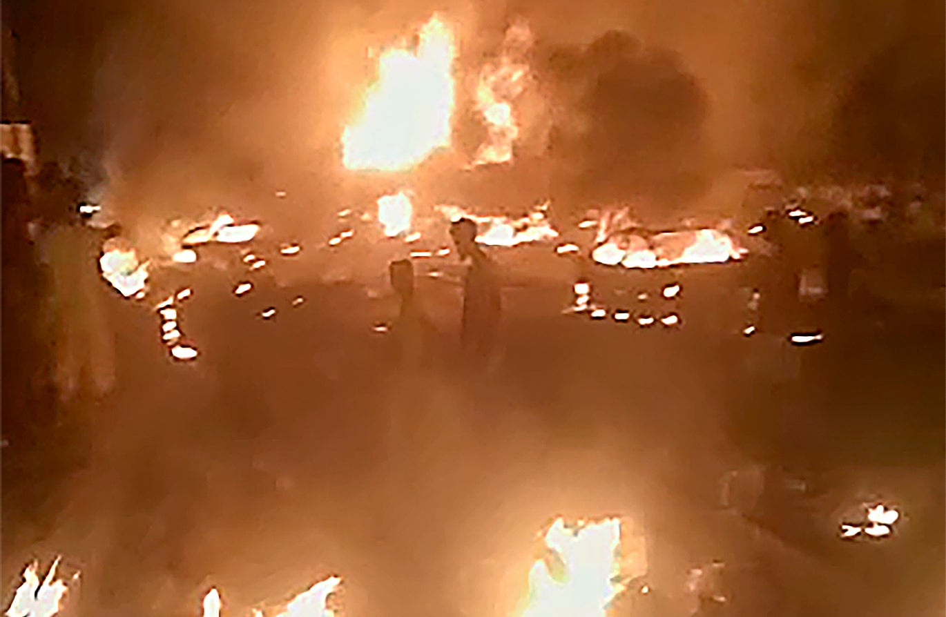 People walk by burning debris following the Freetown explosion