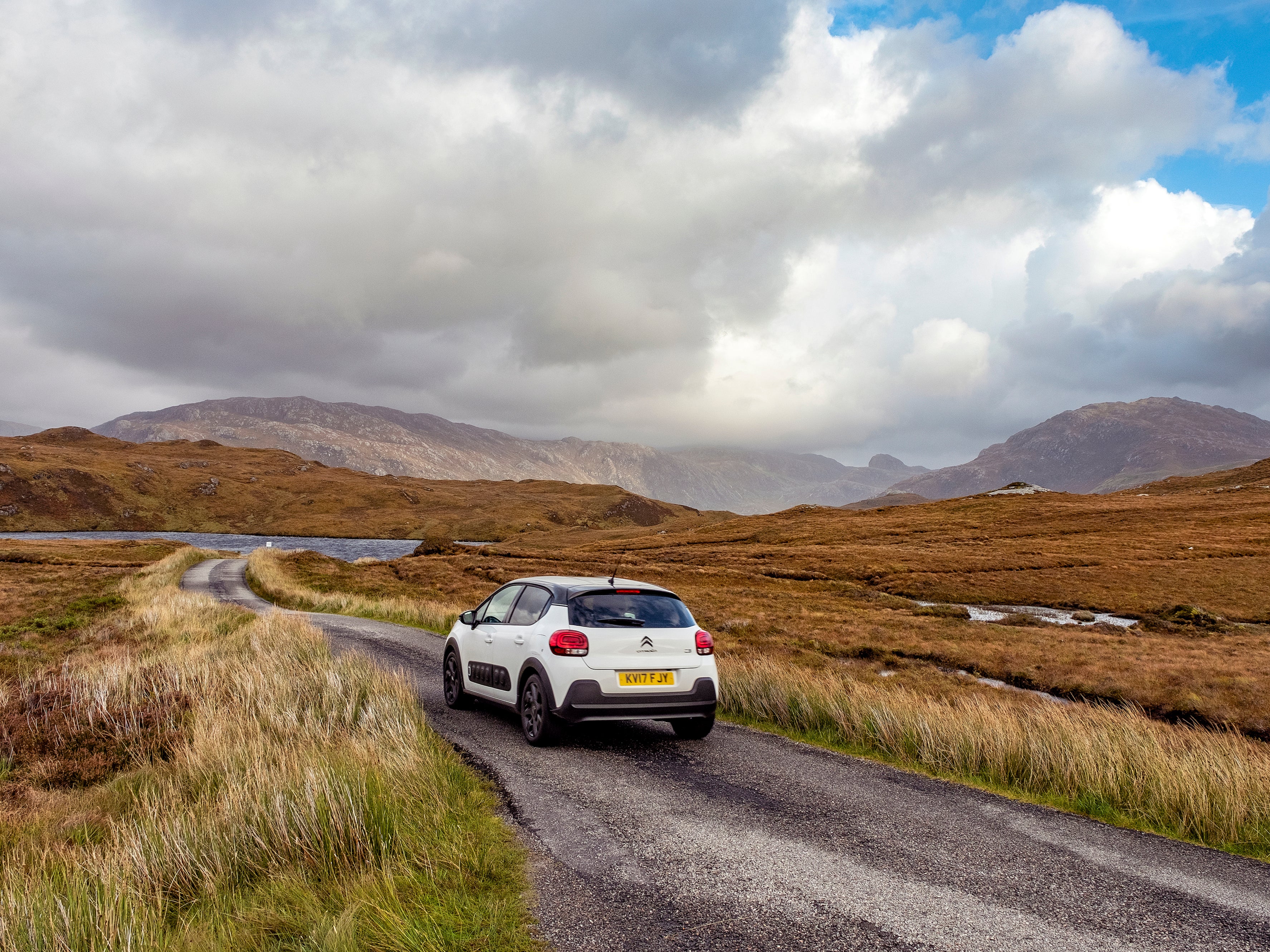 A car navigates a British country road in autumn