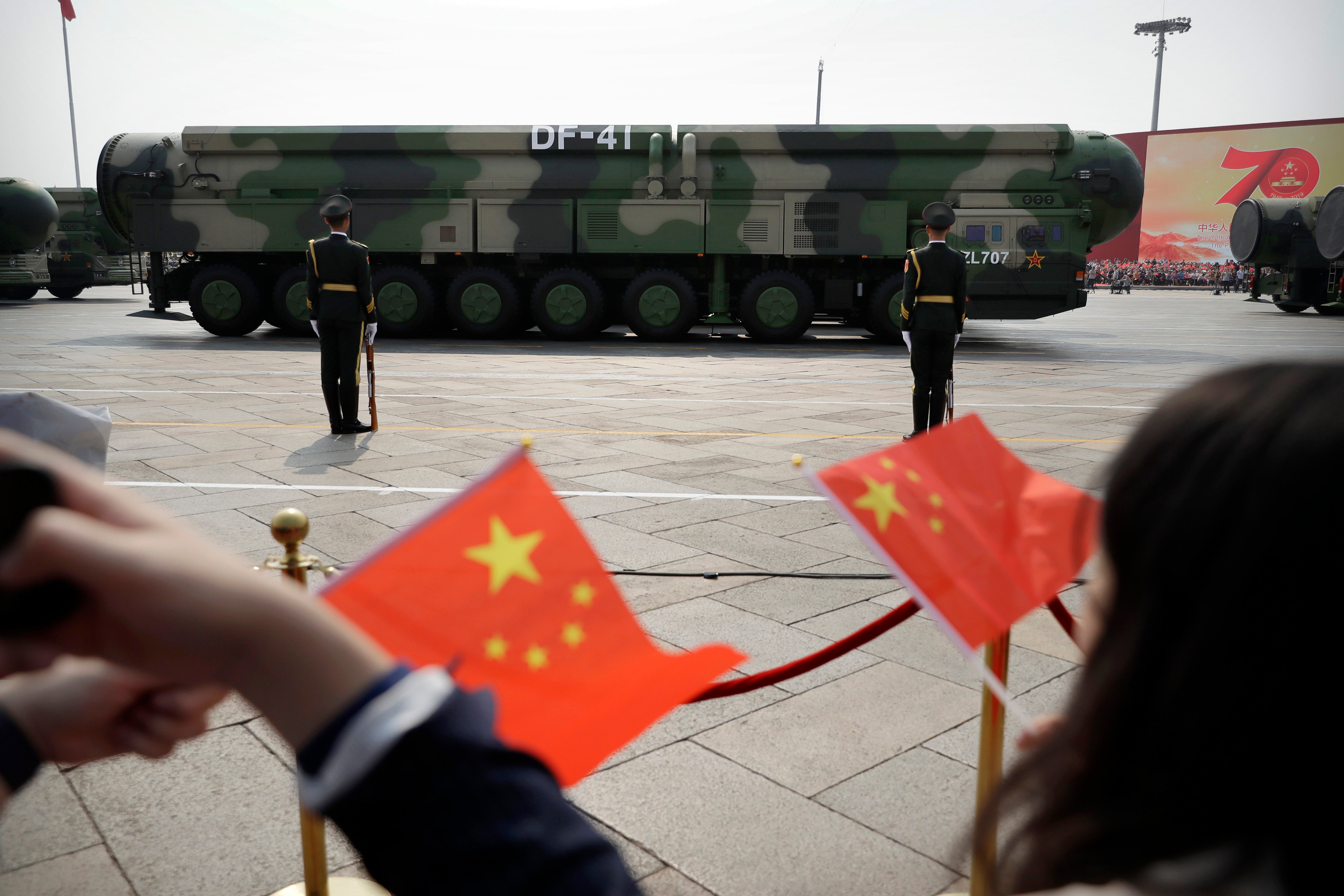 Spectators wave Chinese flags during a parade in Beijing