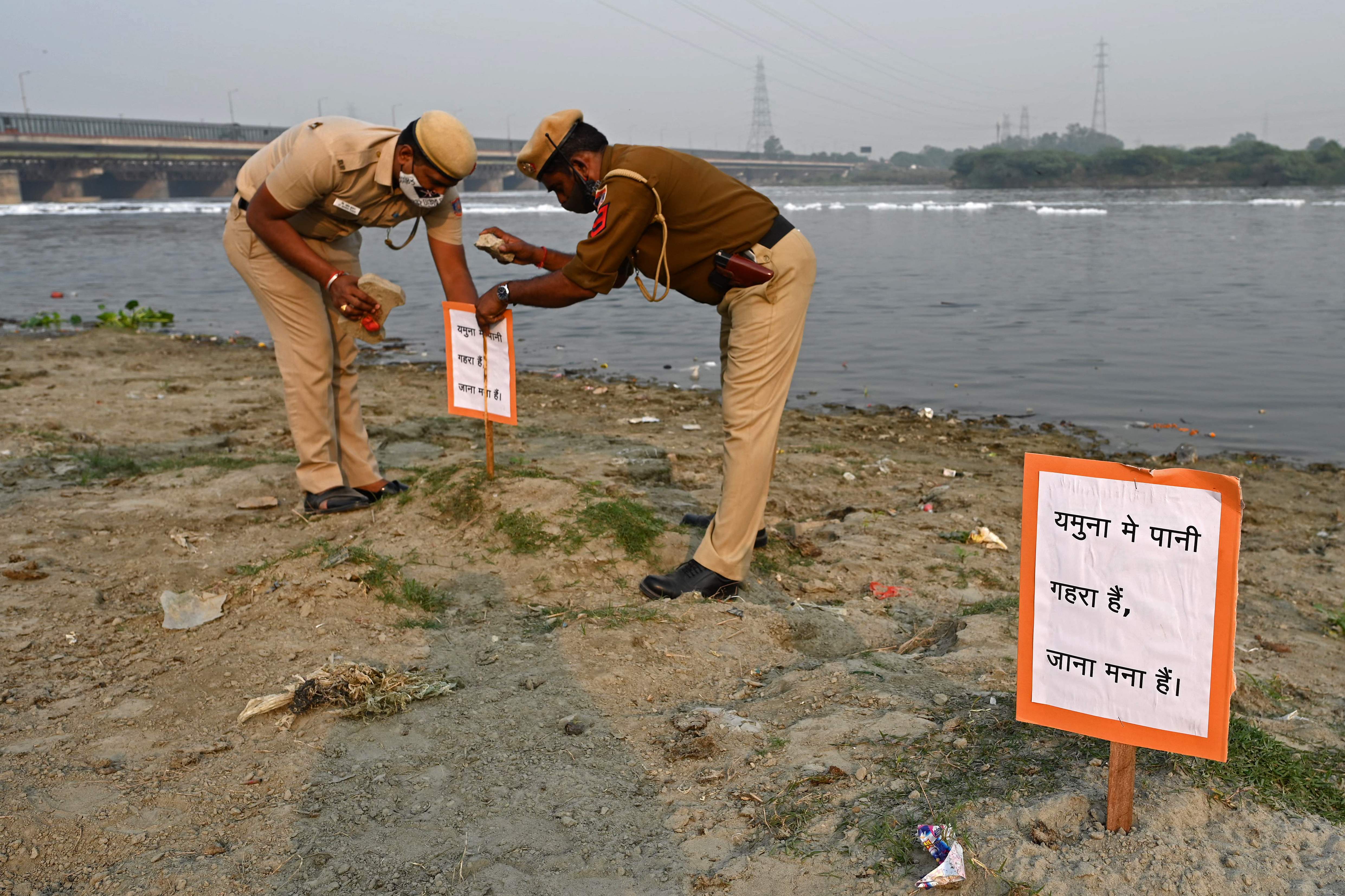 Policemen install a placard which reads ‘The water is deep in the Yamuna. Do not enter’ for devotees along the banks of the Yamuna in Delhi on 10 November 2021