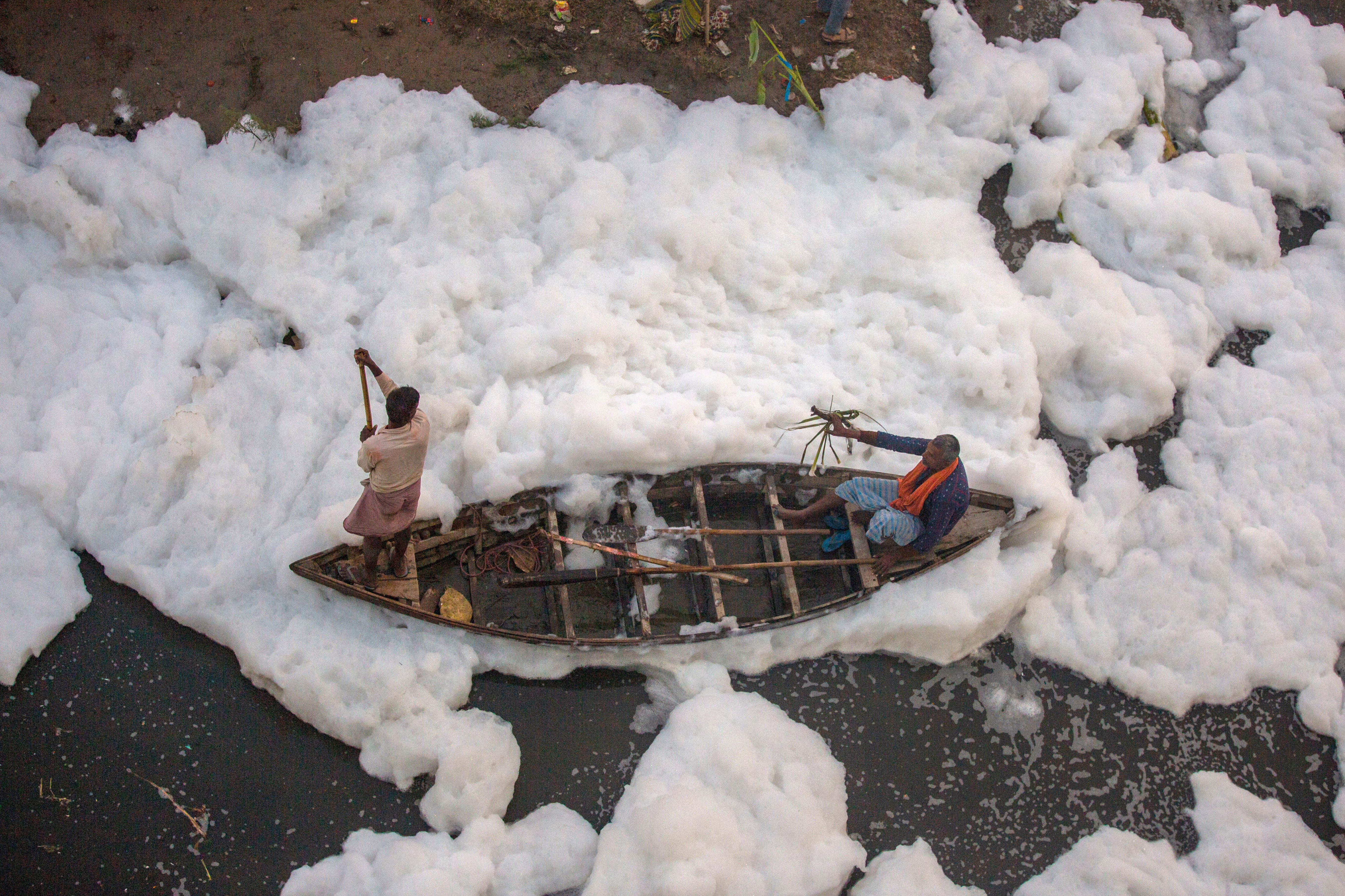 A man rows a boat in Yamuna River, covered by a chemical foam caused by industrial and domestic pollution, in Delhi.