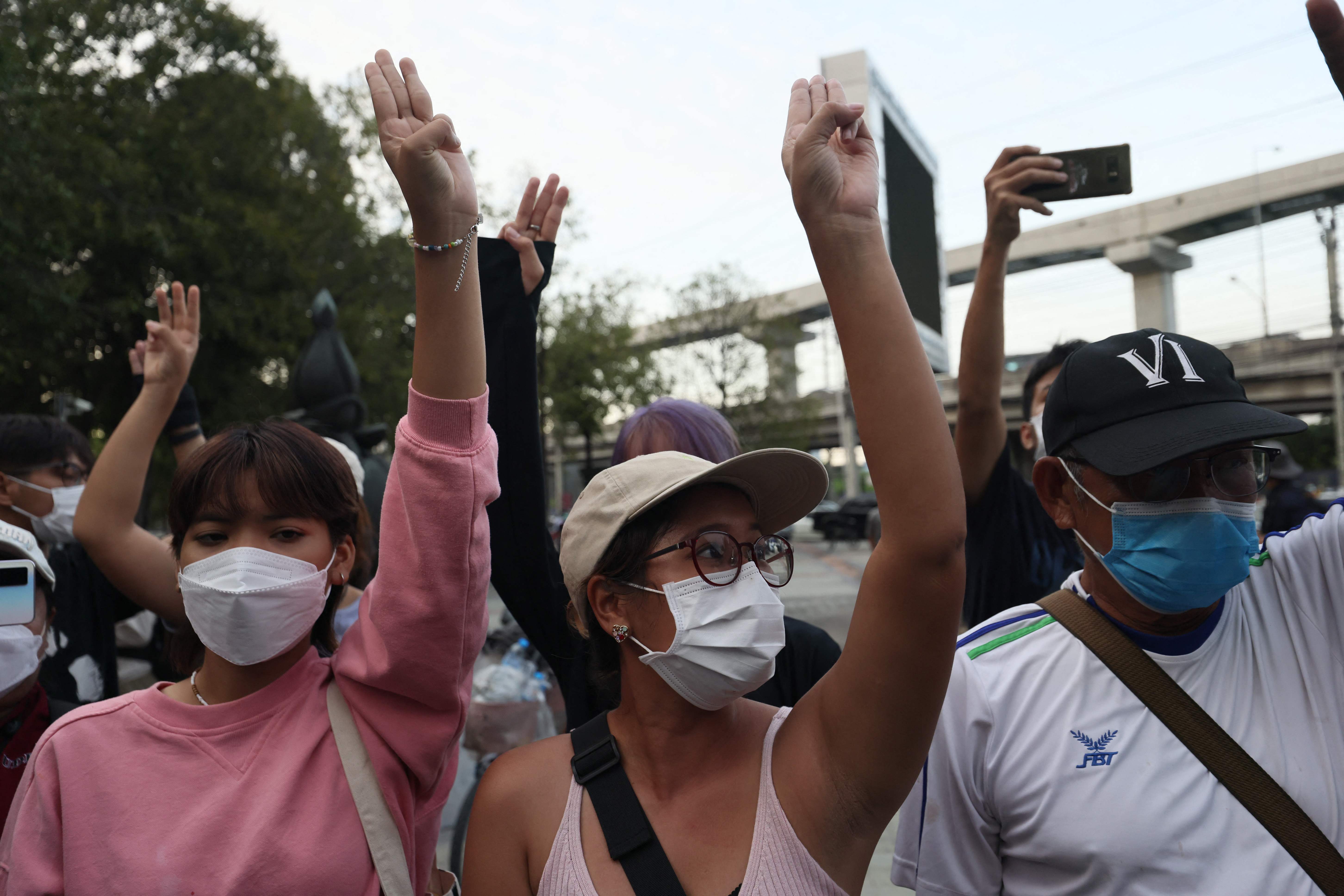 Protesters hold up the three finger salute outside the Constitutional Court of Thailand in Bangkok