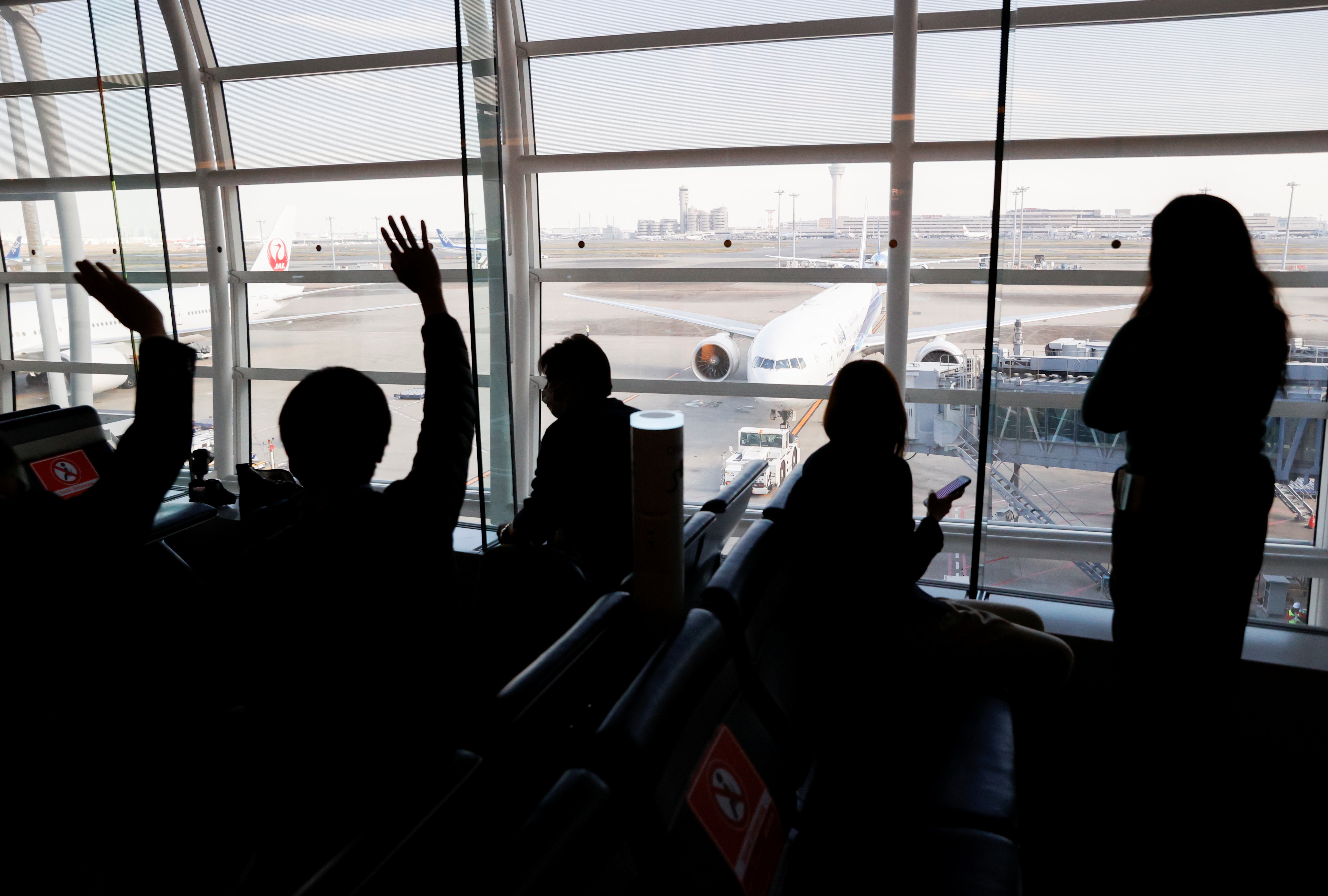 People wave as the ANA flight carrying Mako Komuro and her newly married husband Kei to New York to start their new life in the US leaves its gate at Haneda airport