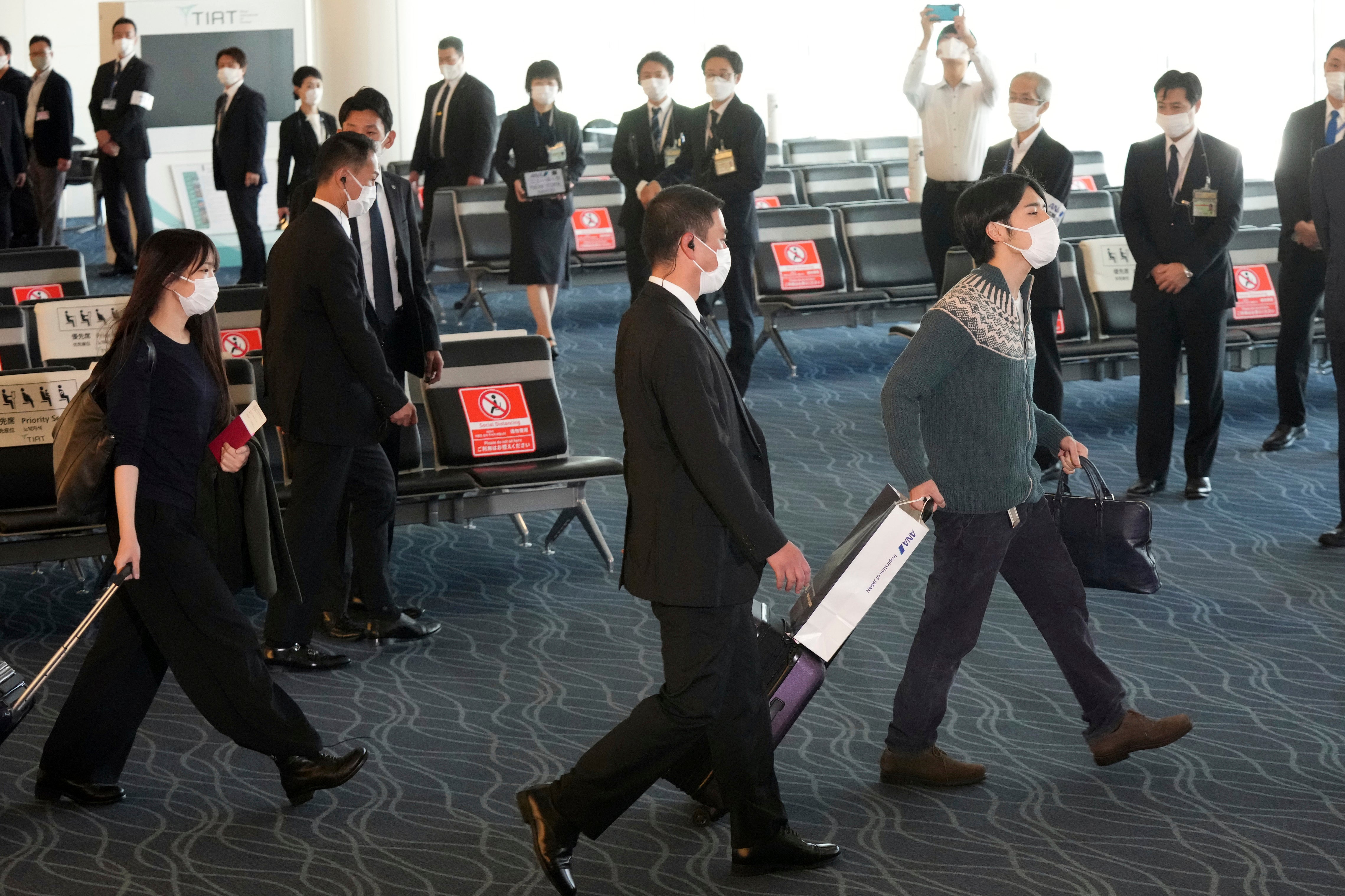 Japan's former Princess Mako, left, the elder daughter of Crown Prince Akishino, and her husband Kei Komuro, right, walk to board a plane to New York