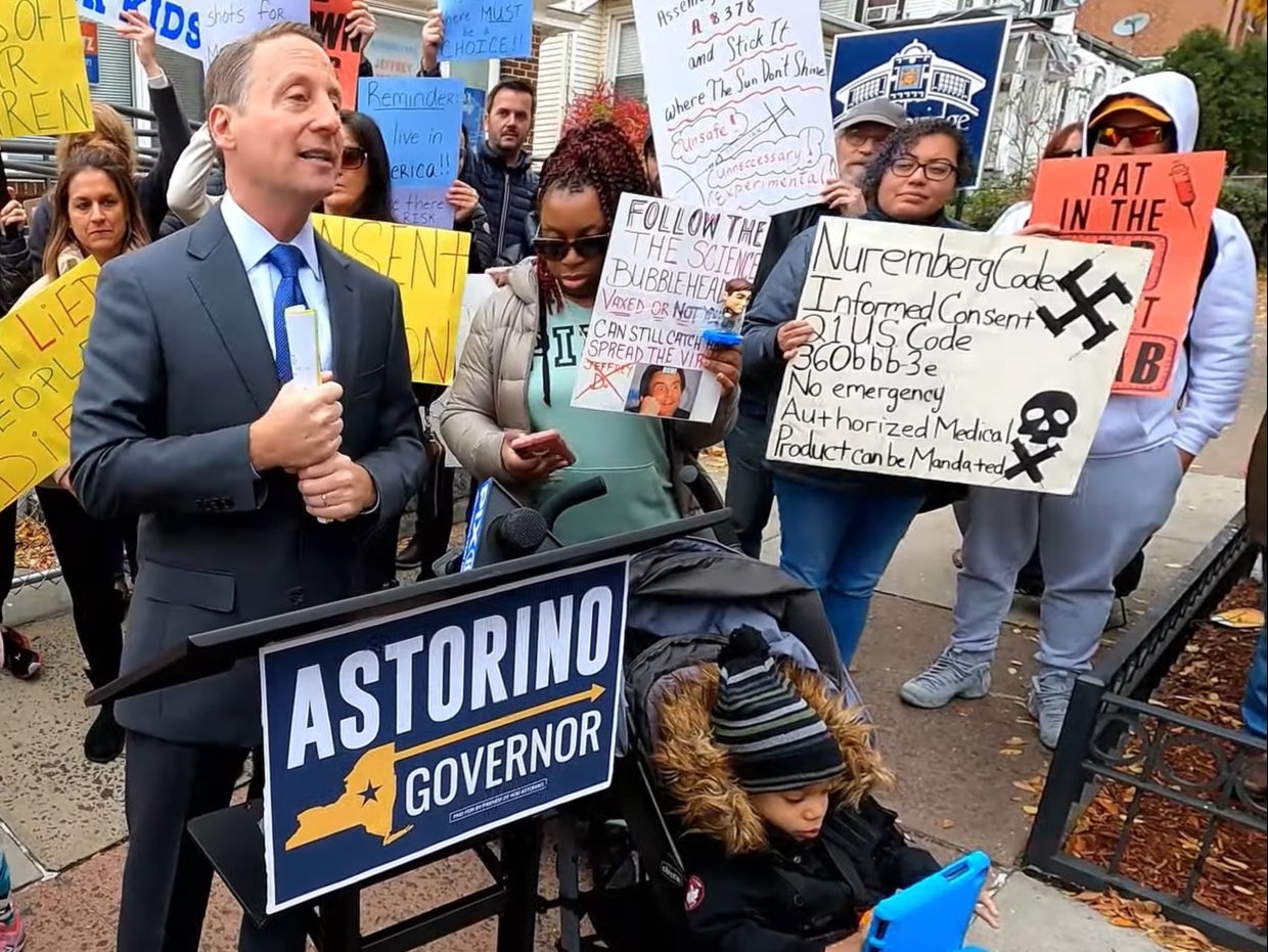 Rob Astorino, a Republican politician, speaks just feet away from a woman holding a swastika sign, who he later claimed he had not noticed