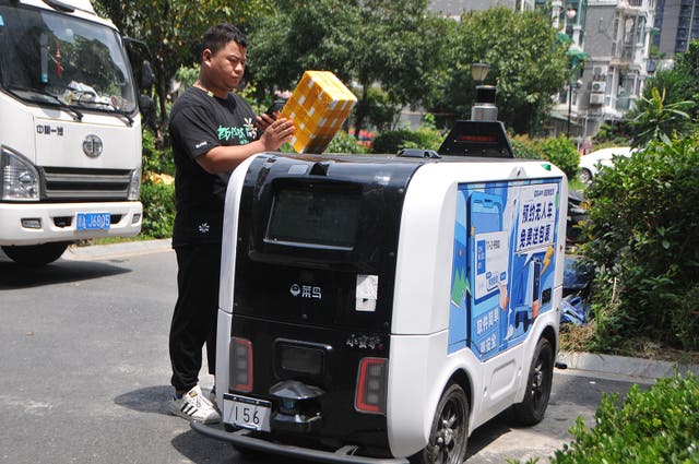 <p>A man picks up a parcel from a Cainiao autonomous delivery vehicle at a community in Hangzhou, Zhejiang province, in August</p>